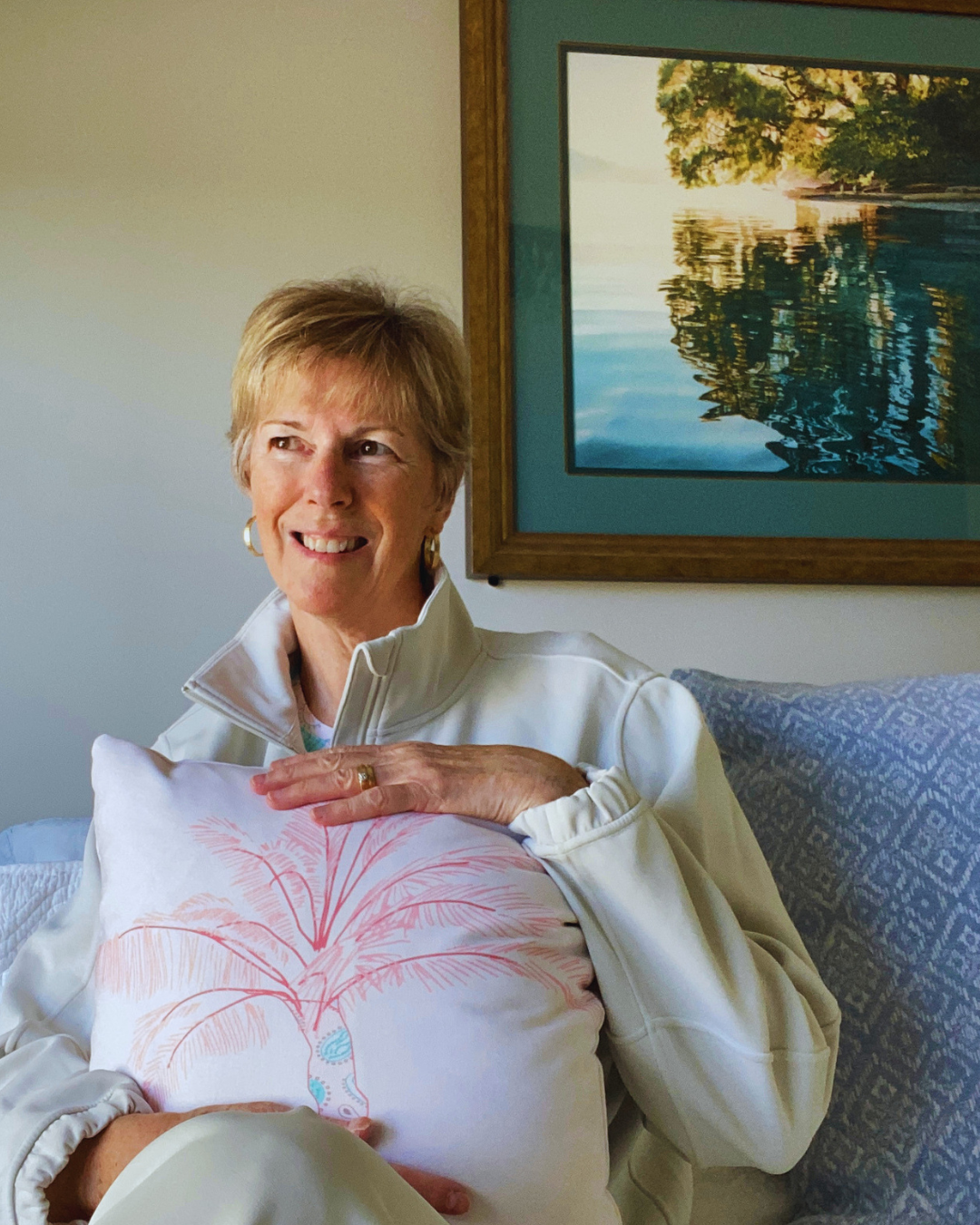 Artist and designer Kelly Edmonds holding a palm tree pillow from the Caicos Beach collection.