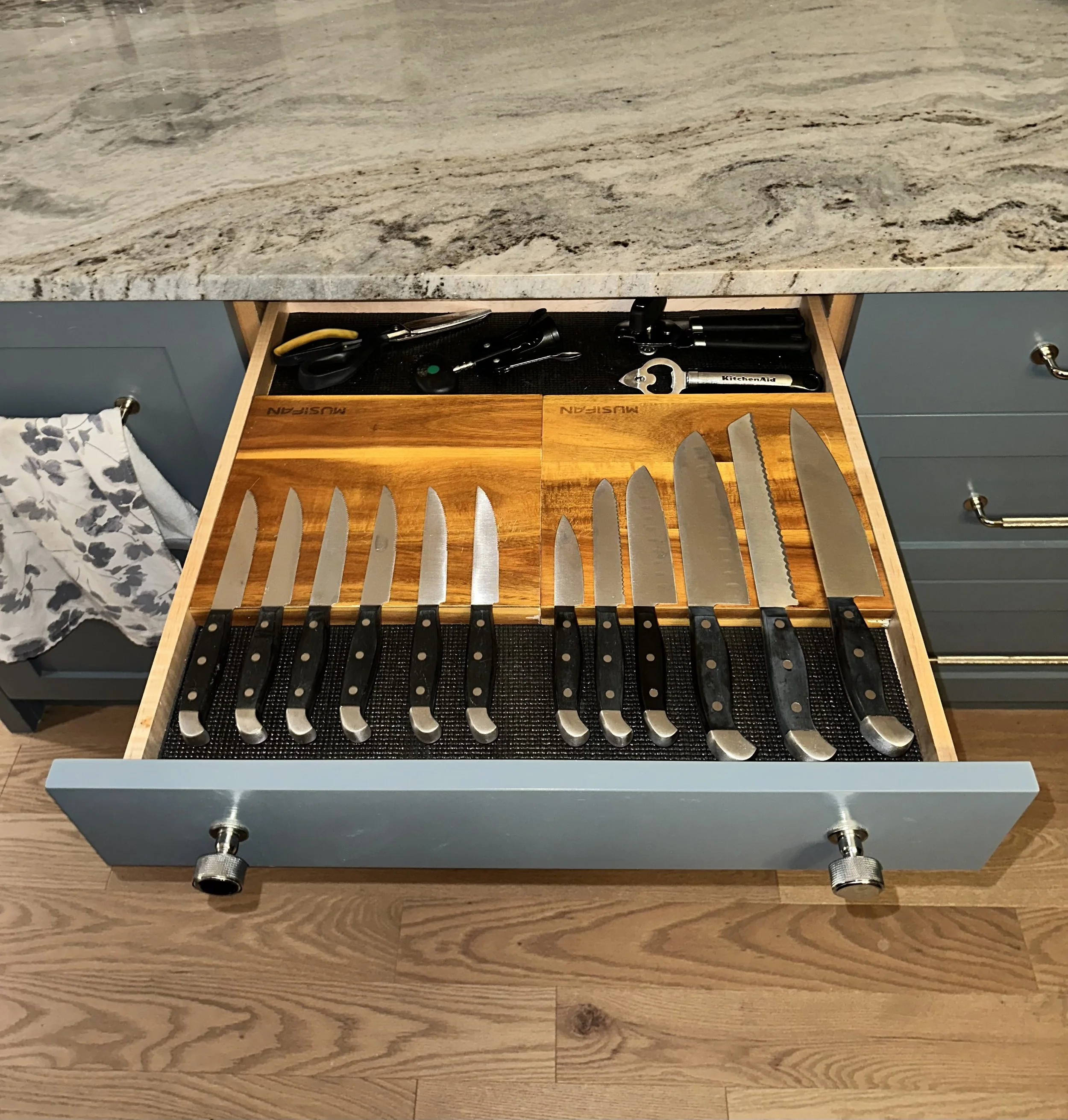 Open kitchen drawer with magnetic block holder for knives, scissors, and a corkscrew.