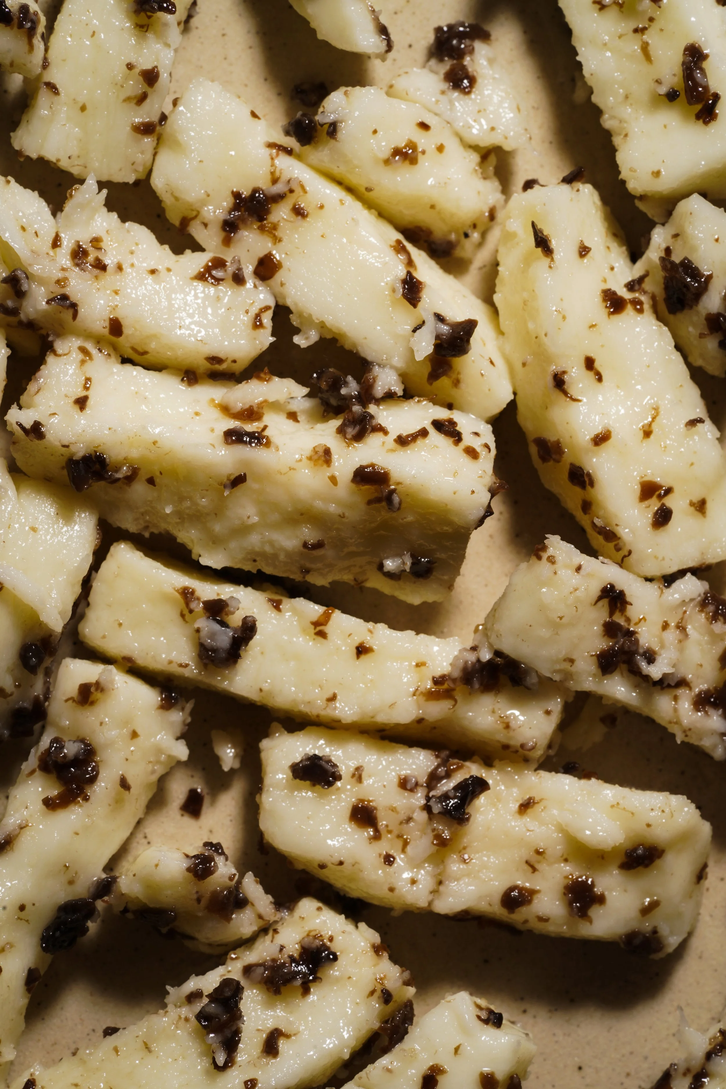 Pieces of cooked or baked potato sprinkled with black pepper.