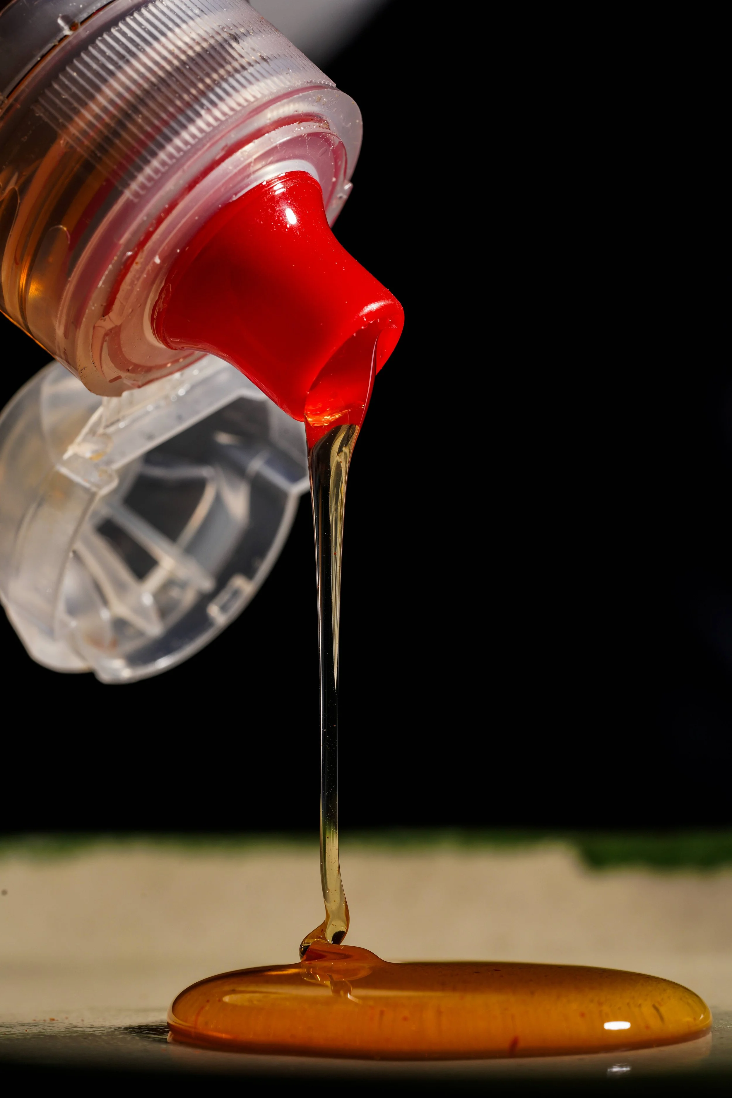 A close-up of caramel syrup flowing from a squeeze bottle onto a surface.