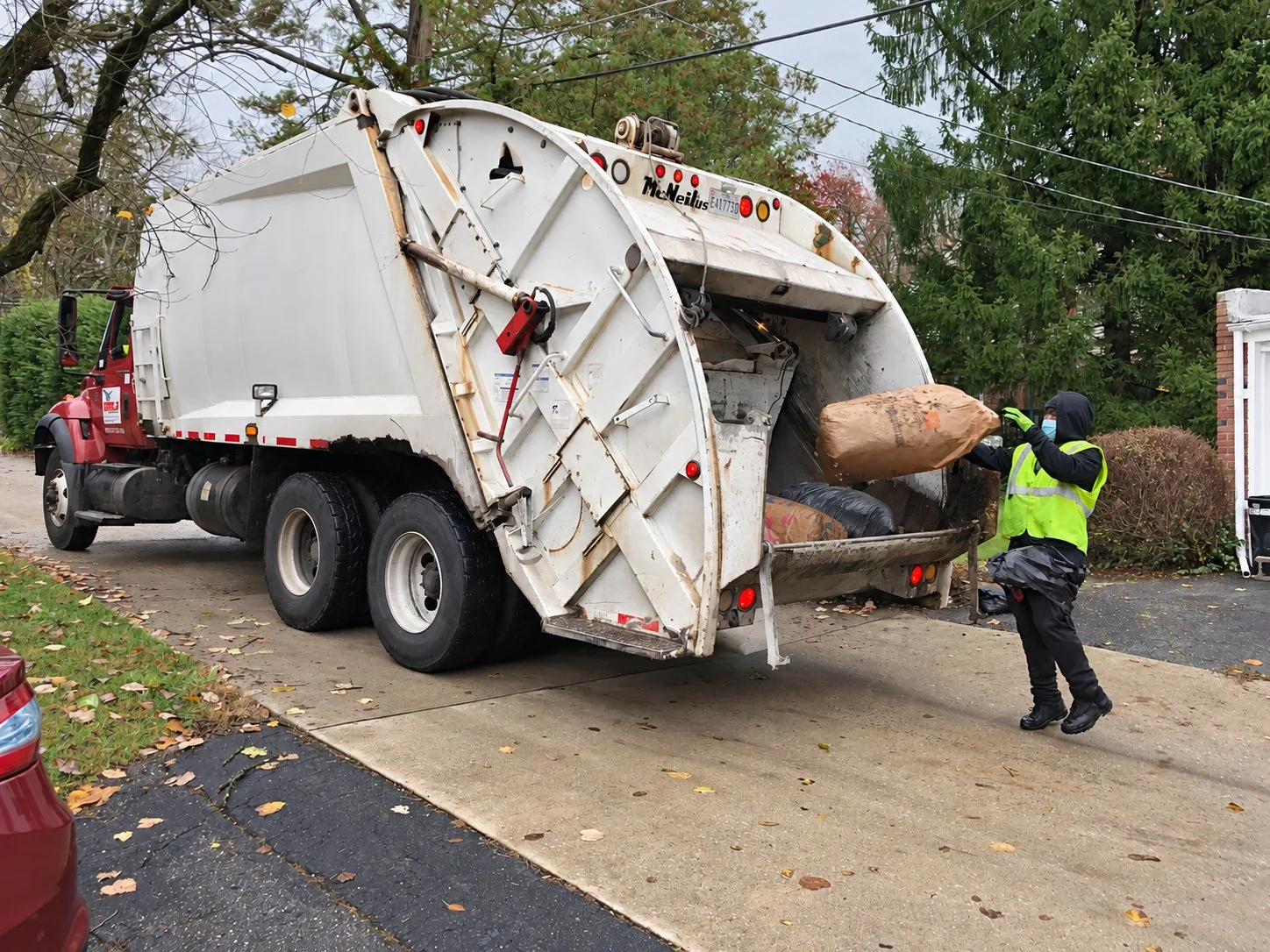 Rear-load collection crew loading bagged yard waste in Baltimore County, Maryland