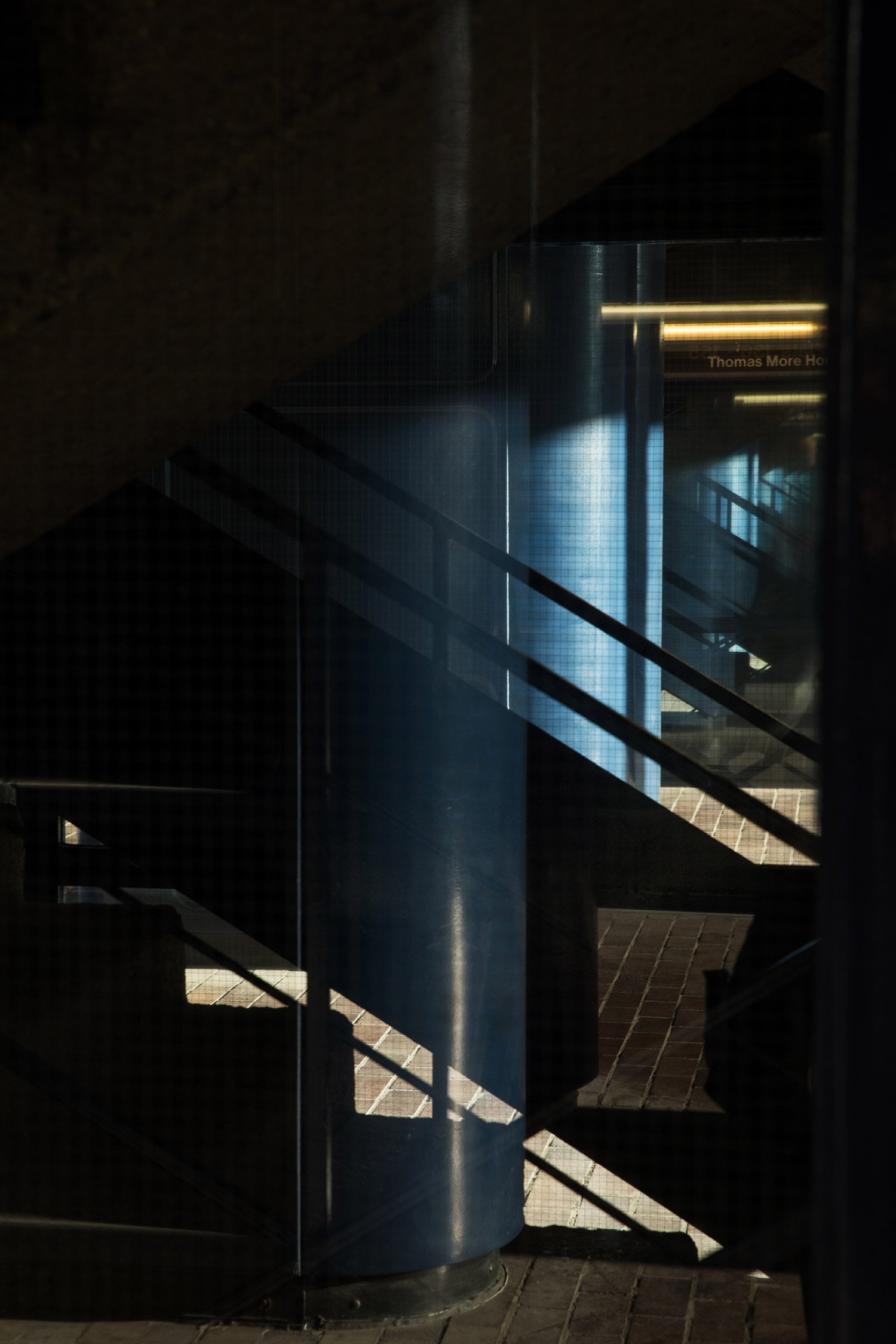 Staircase and concrete passage illuminated by cool blue light at The Barbican.