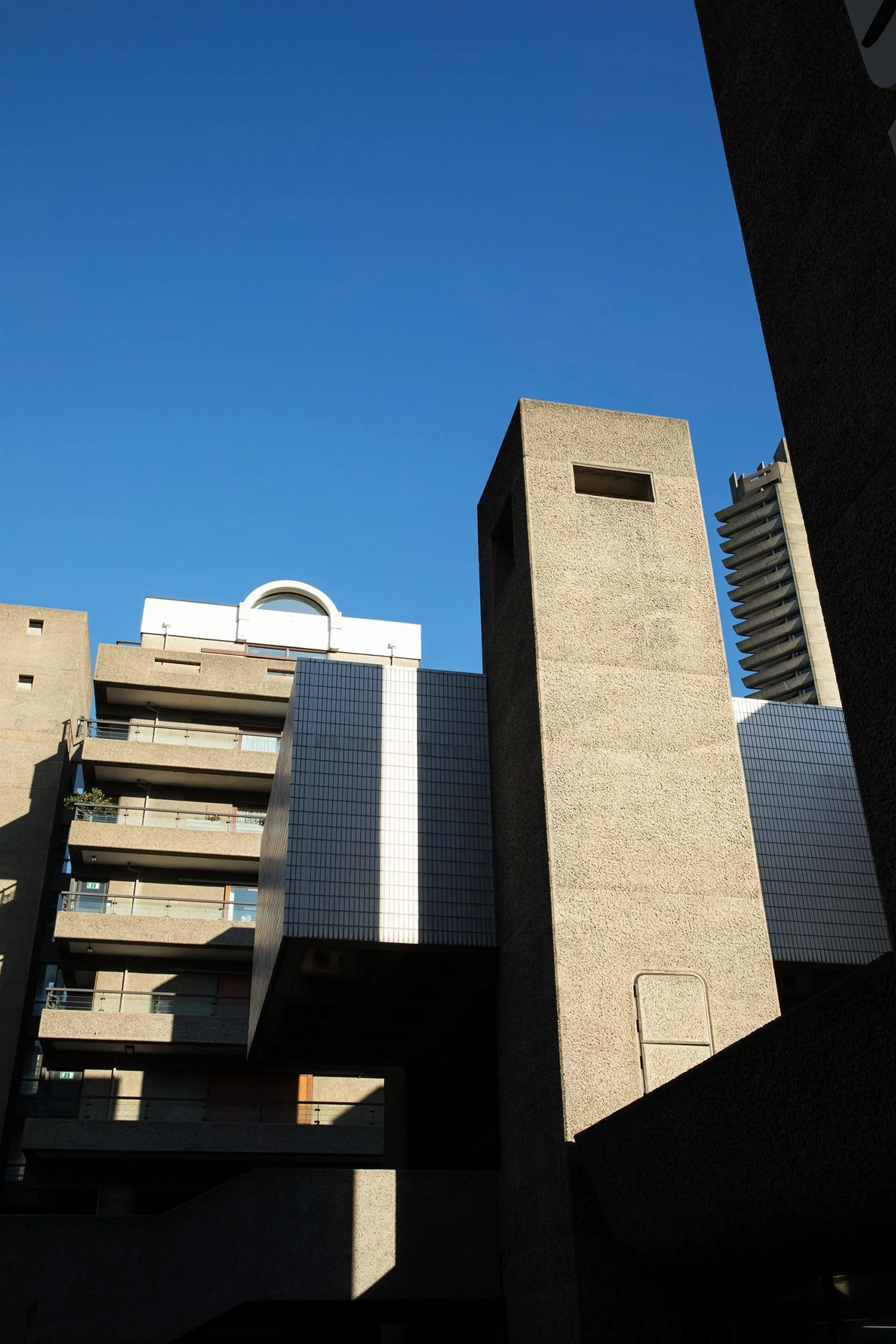 Barbican residential towers viewed from below, emphasising their vertical concrete forms.