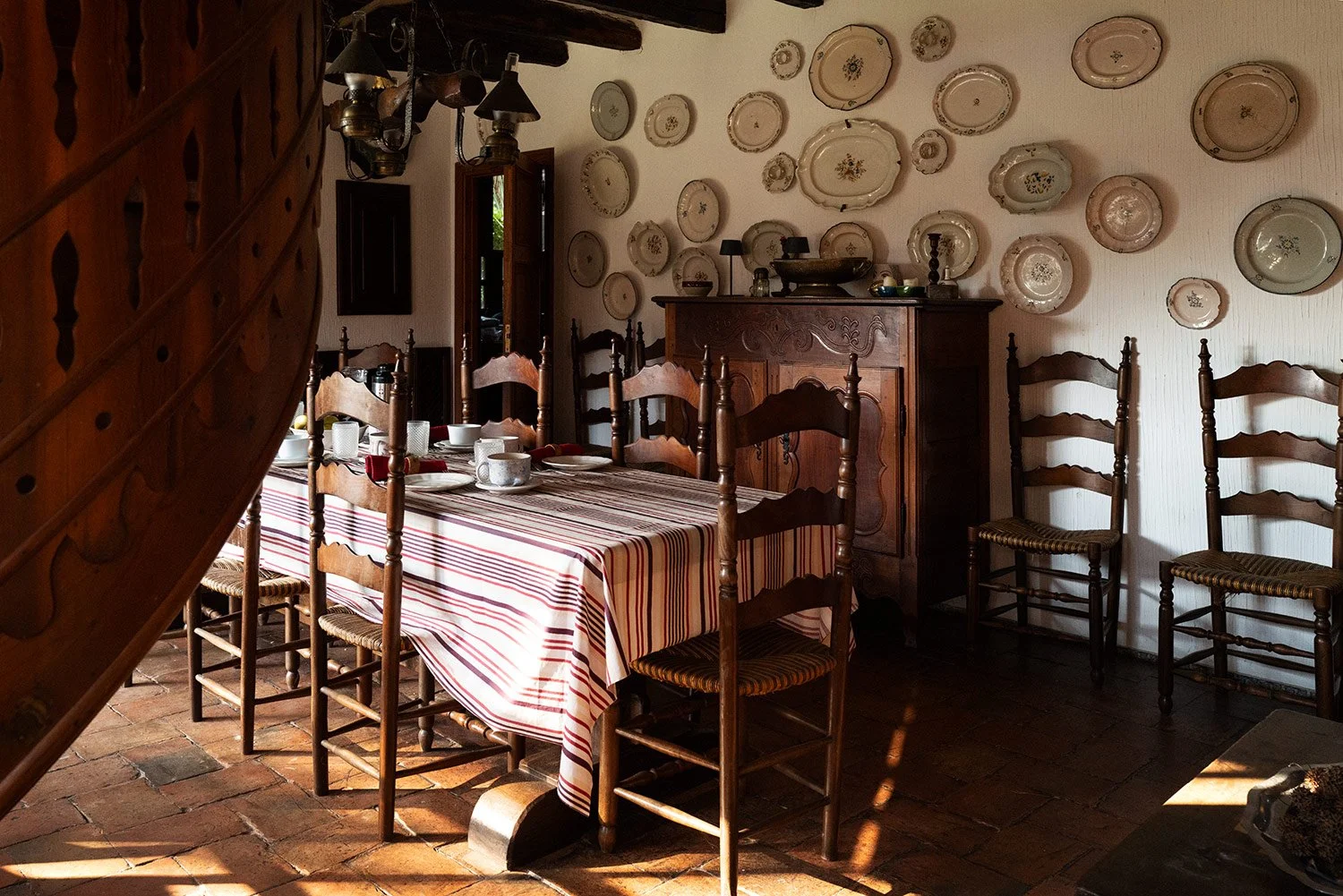 Dining table beneath a wall display of decorative plates in the character-filled coastal home.