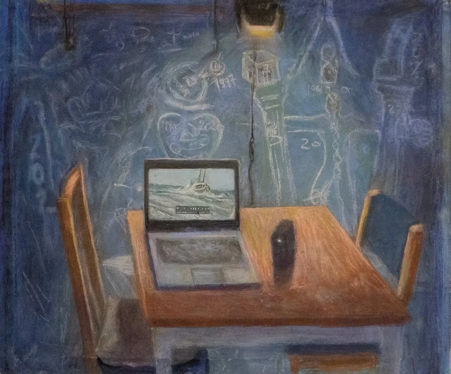 A wooden table with a laptop, a computer mouse, and a speaker in a room with dark blue walls covered in chalk sketches of clocks, faces, and abstract shapes.