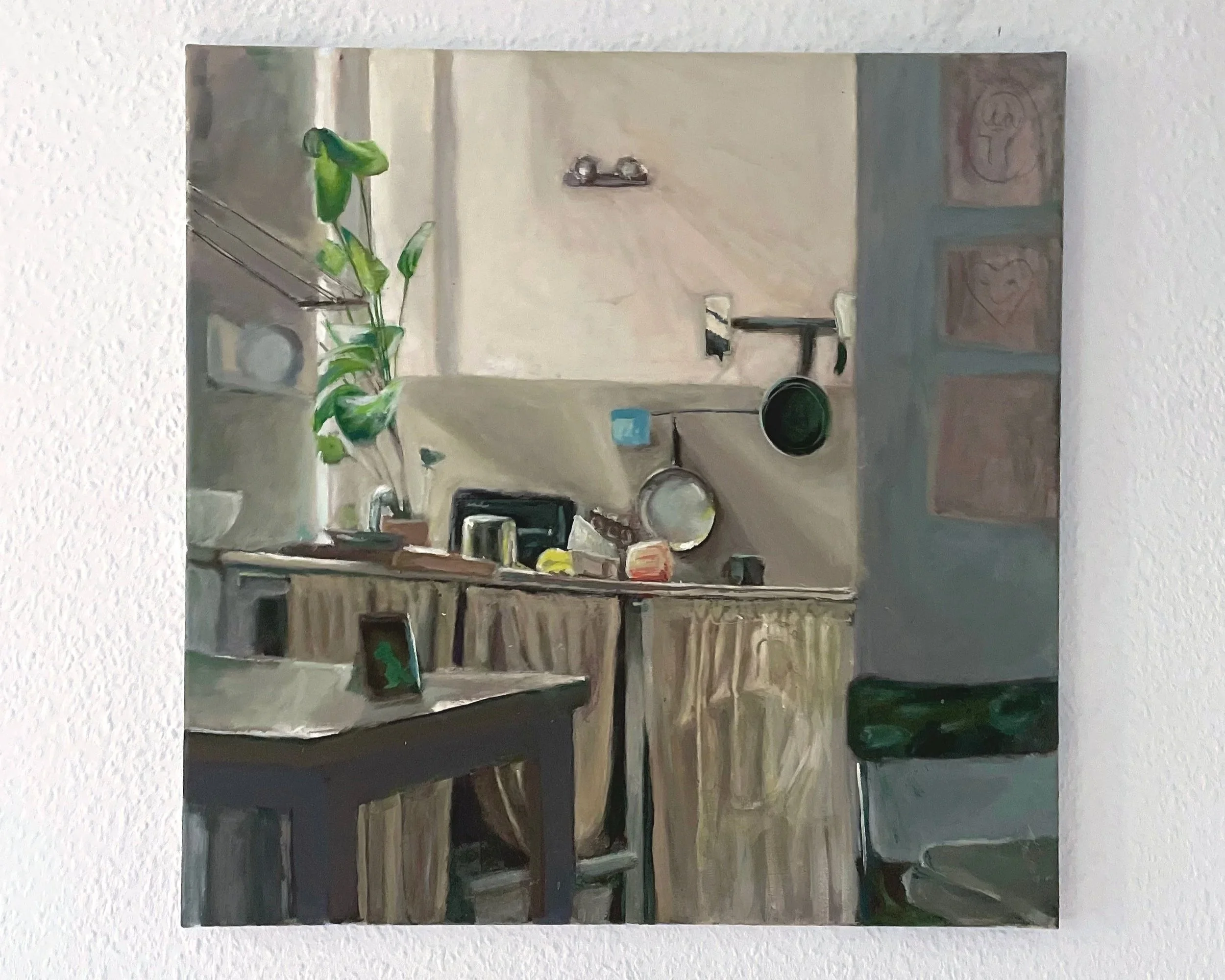 An interior view of a kitchen with a wooden table, various dishes, a plant, and decorative artwork on the walls.