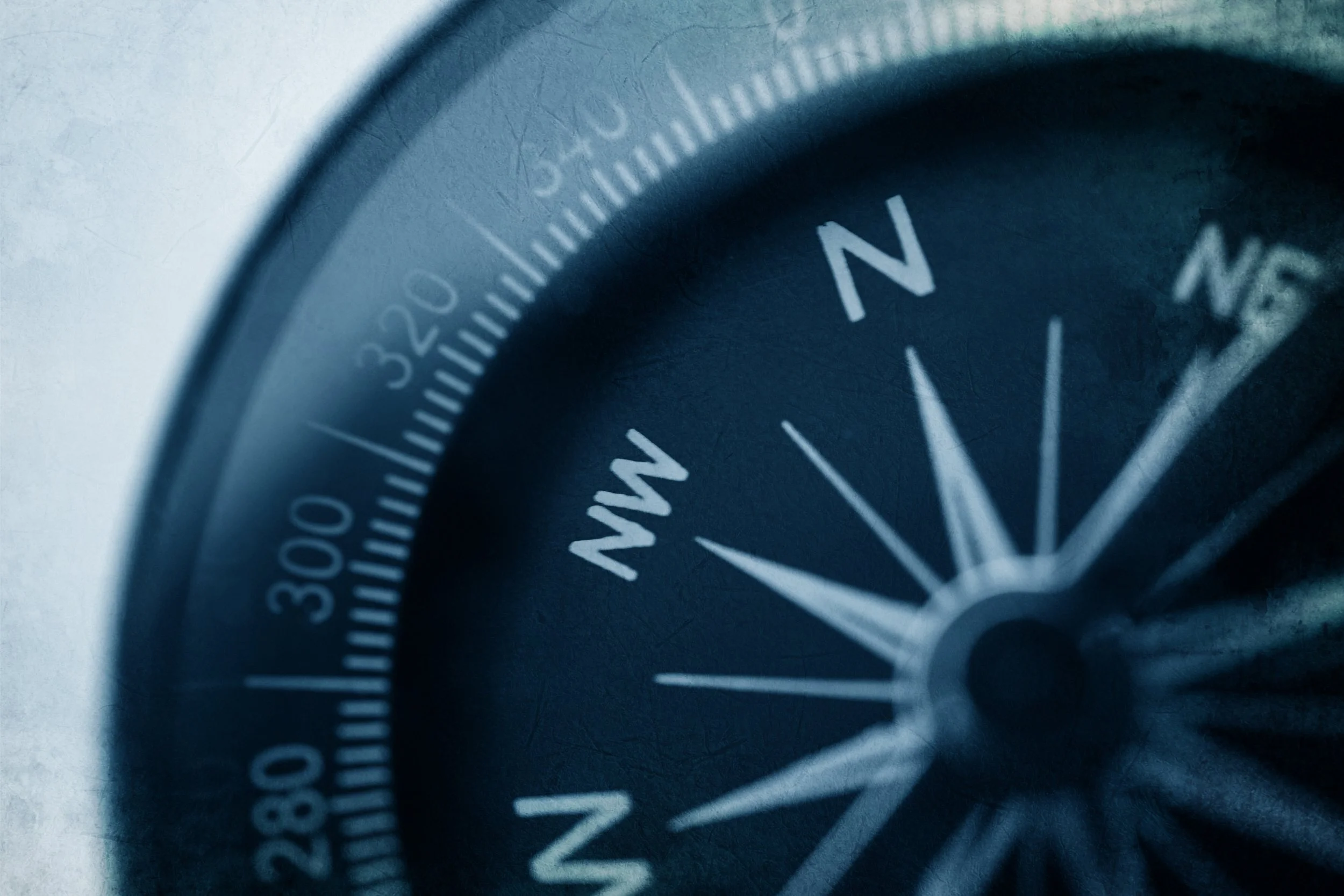 Close-up of a compass with directions, focusing on the 'N' for north.