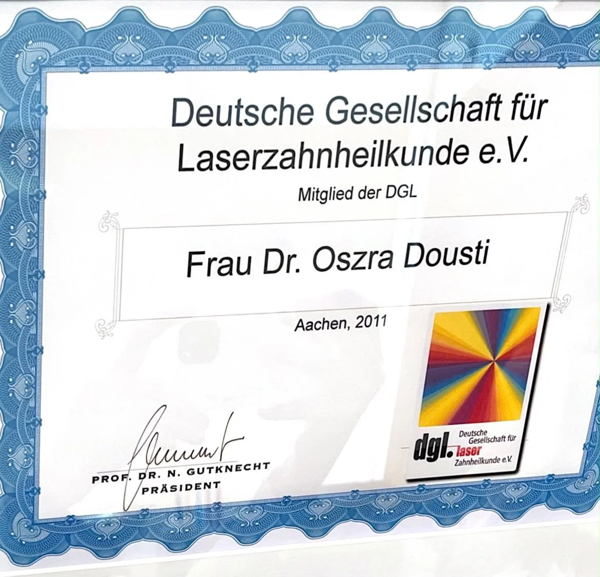 Zertifikat der Deutschen Gesellschaft für Laserzahnheilkunde, ausgestellt an Frau Dr. Oszra Dousti, Aachen 2011, mit blauer Verzierung und farbigem Logo.