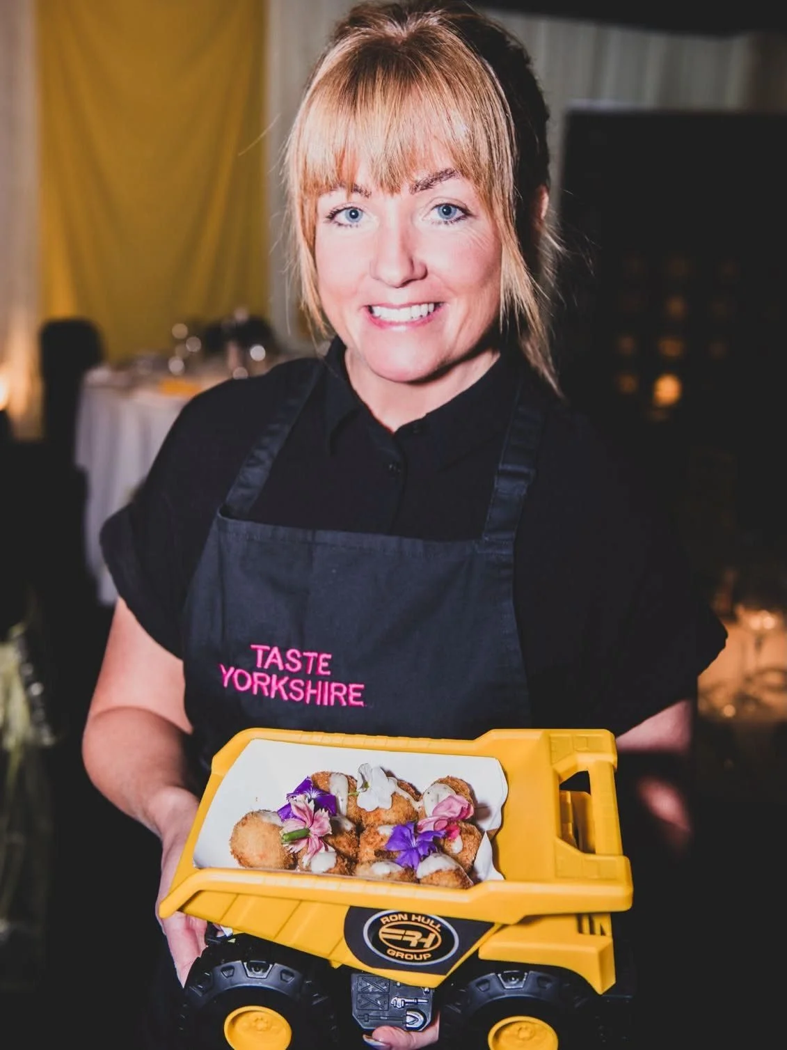 Taste Cuisine team member holding a dumper truck filled with canapés and edible flowers