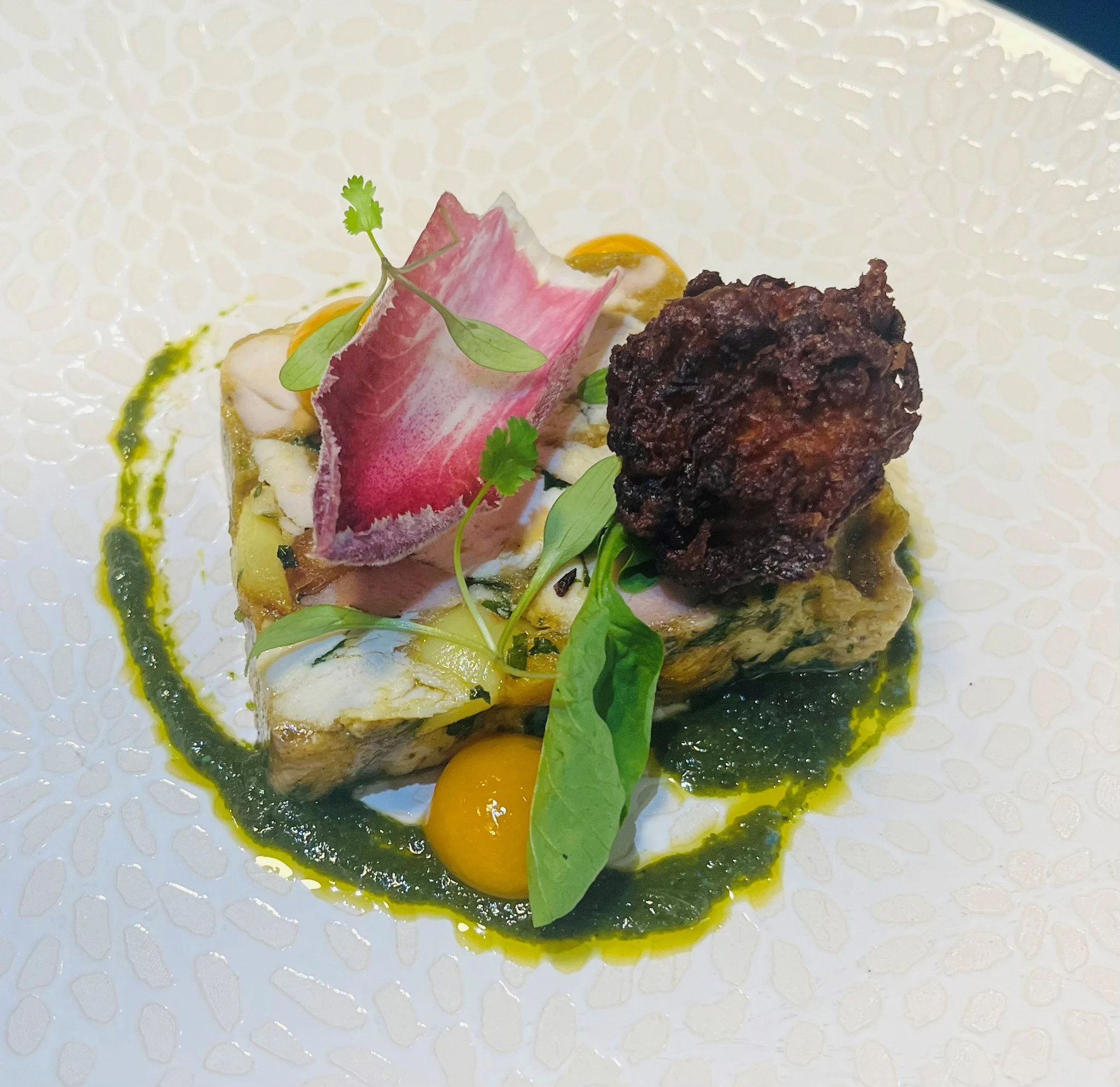Chicken and ham terrine starter with pickled radish, a crisp fritter and herb sauce