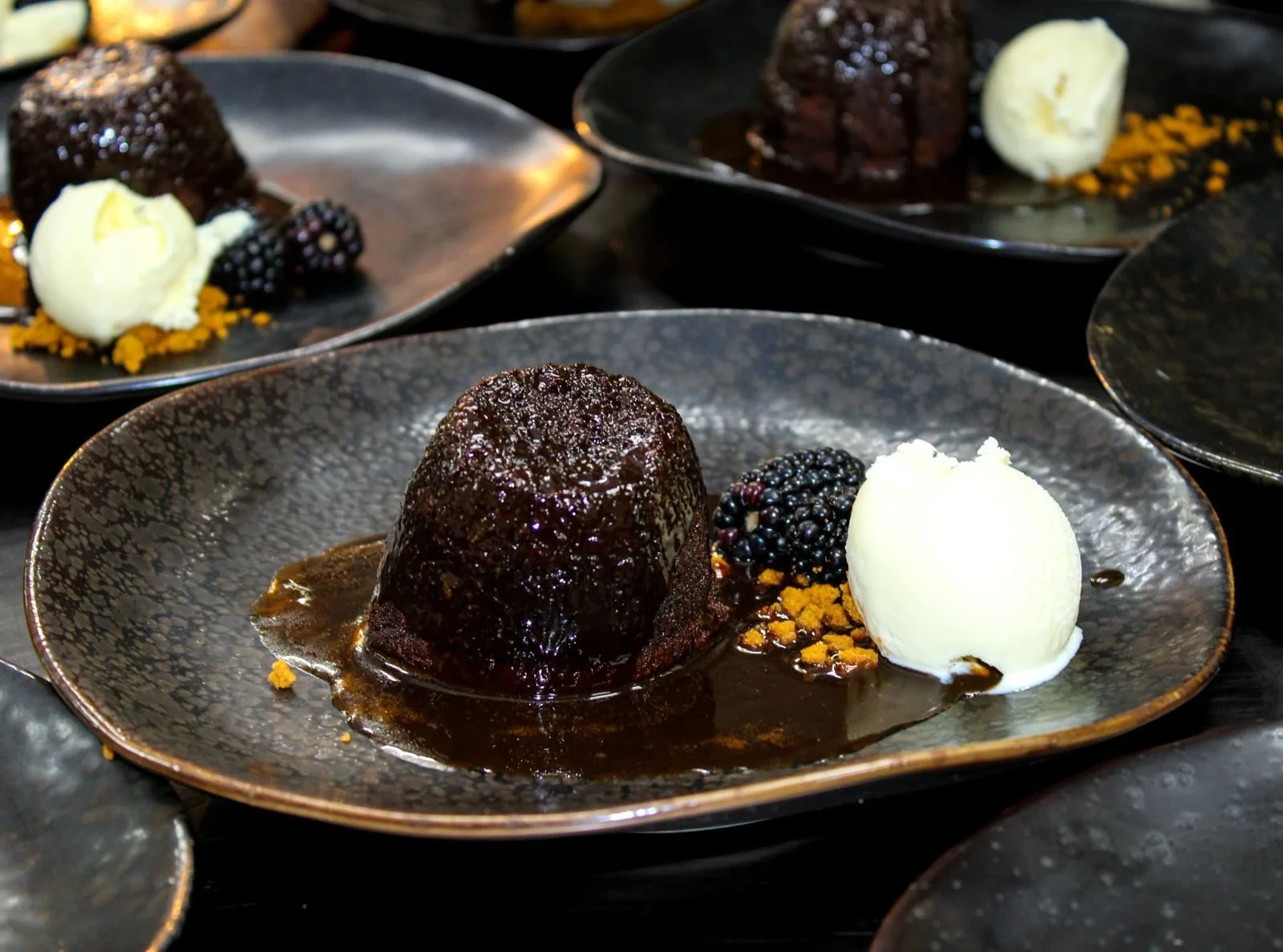 Sticky toffee pudding served with vanilla ice cream and blackberries