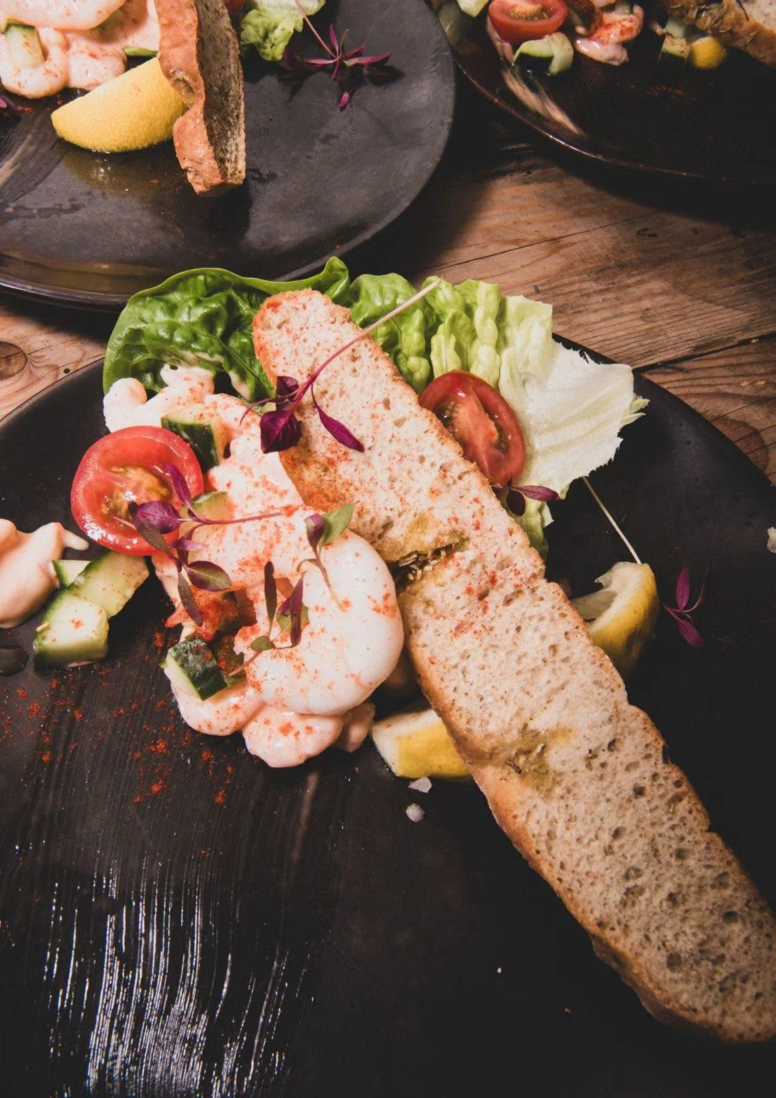 Prawn cocktail starter with granary bread, cucumber, tomato and micro herbs on a dark plate