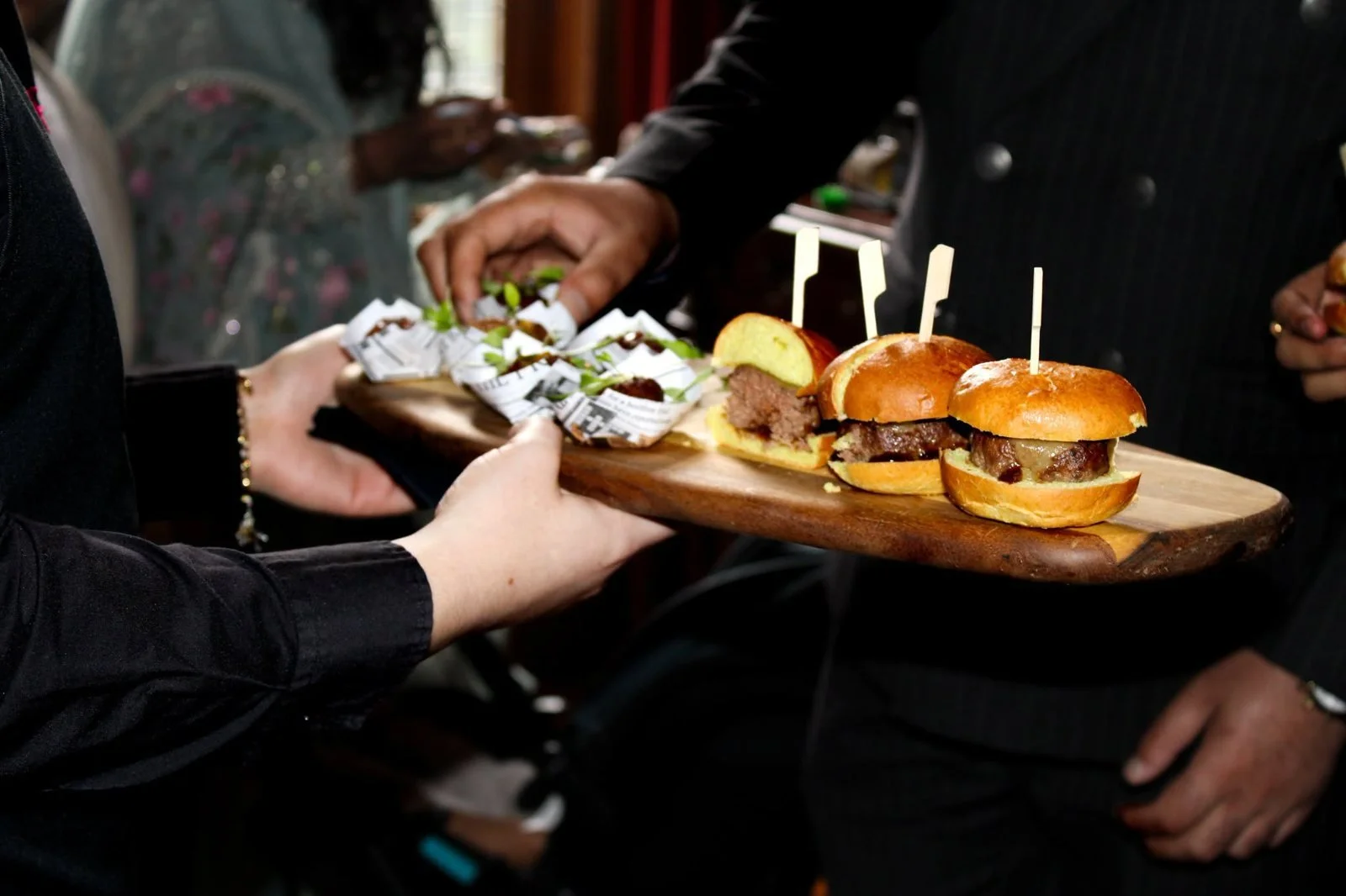Waiting staff serving wedding canapé sliders from a wooden board