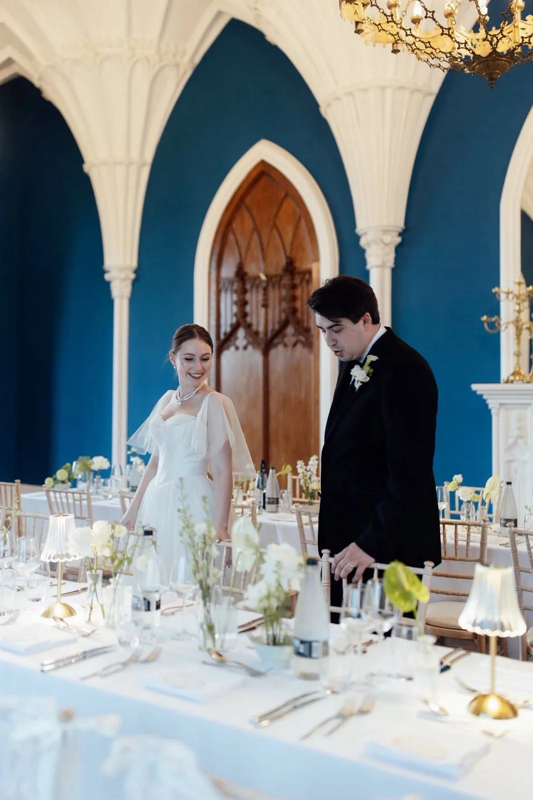 Bride and groom beside the long wedding breakfast table in the blue room at Allerton Castle