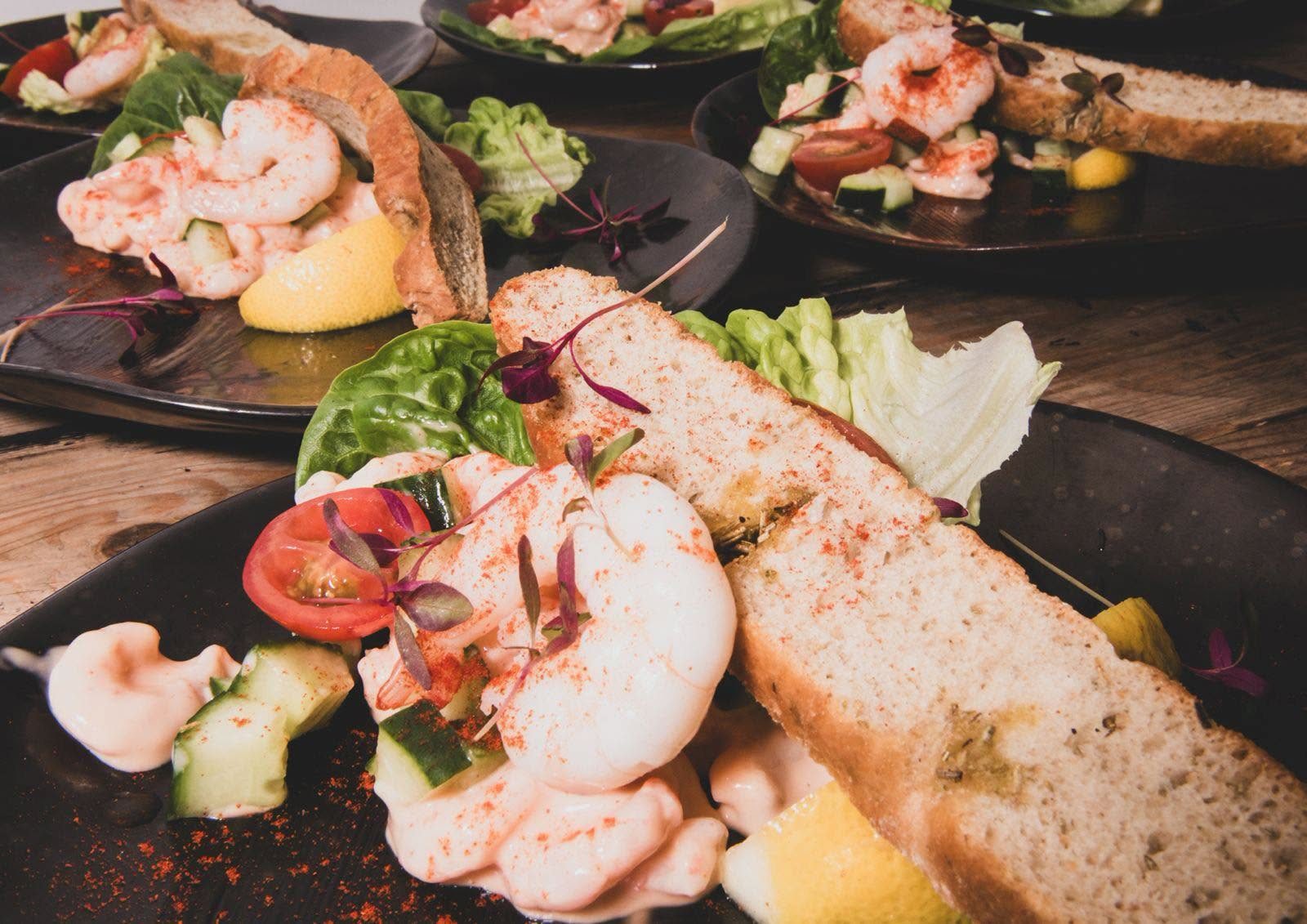 Several prawn cocktail starters lined up on a wooden table ready for service