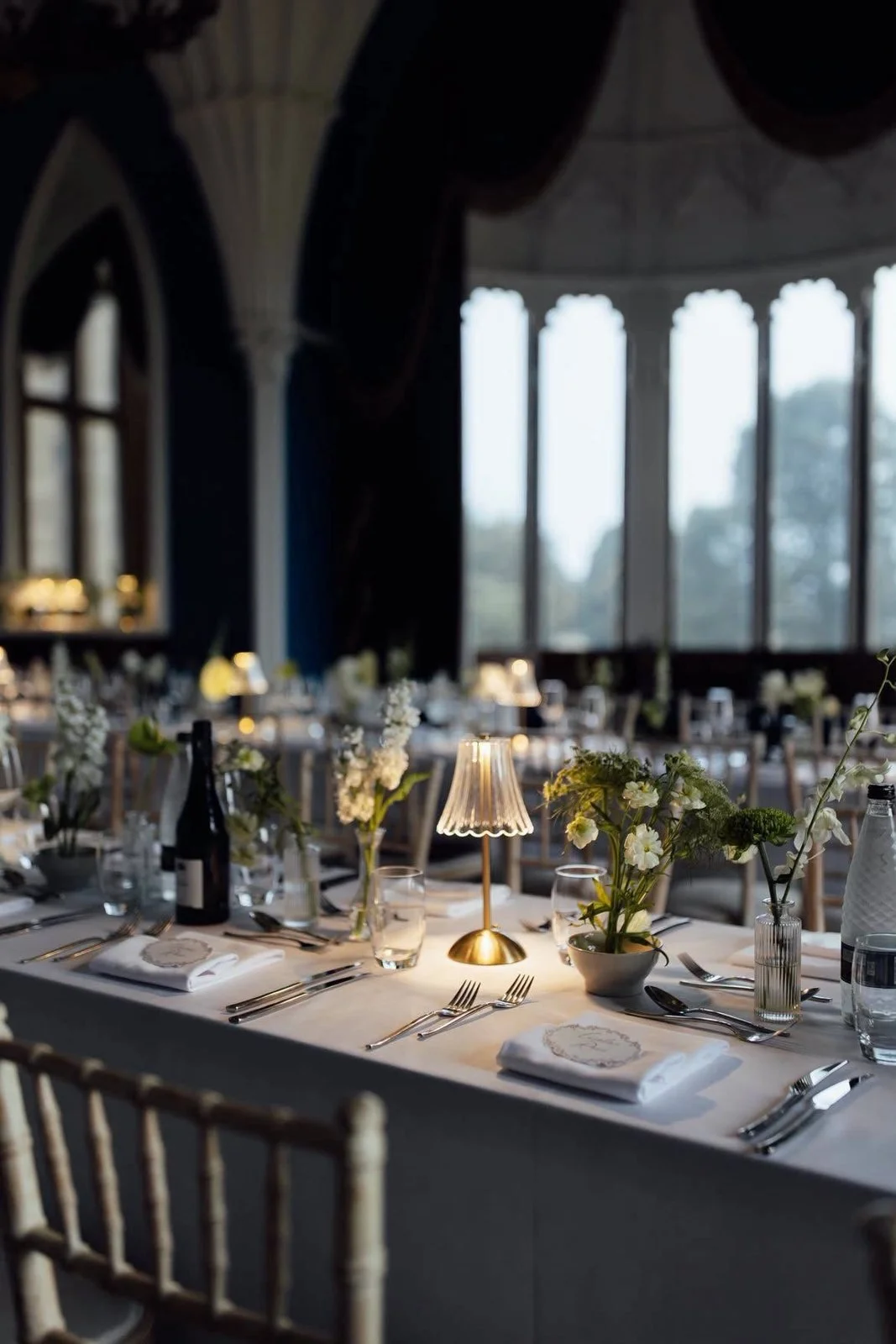 Wedding table set with glassware, flowers and a gold lamp