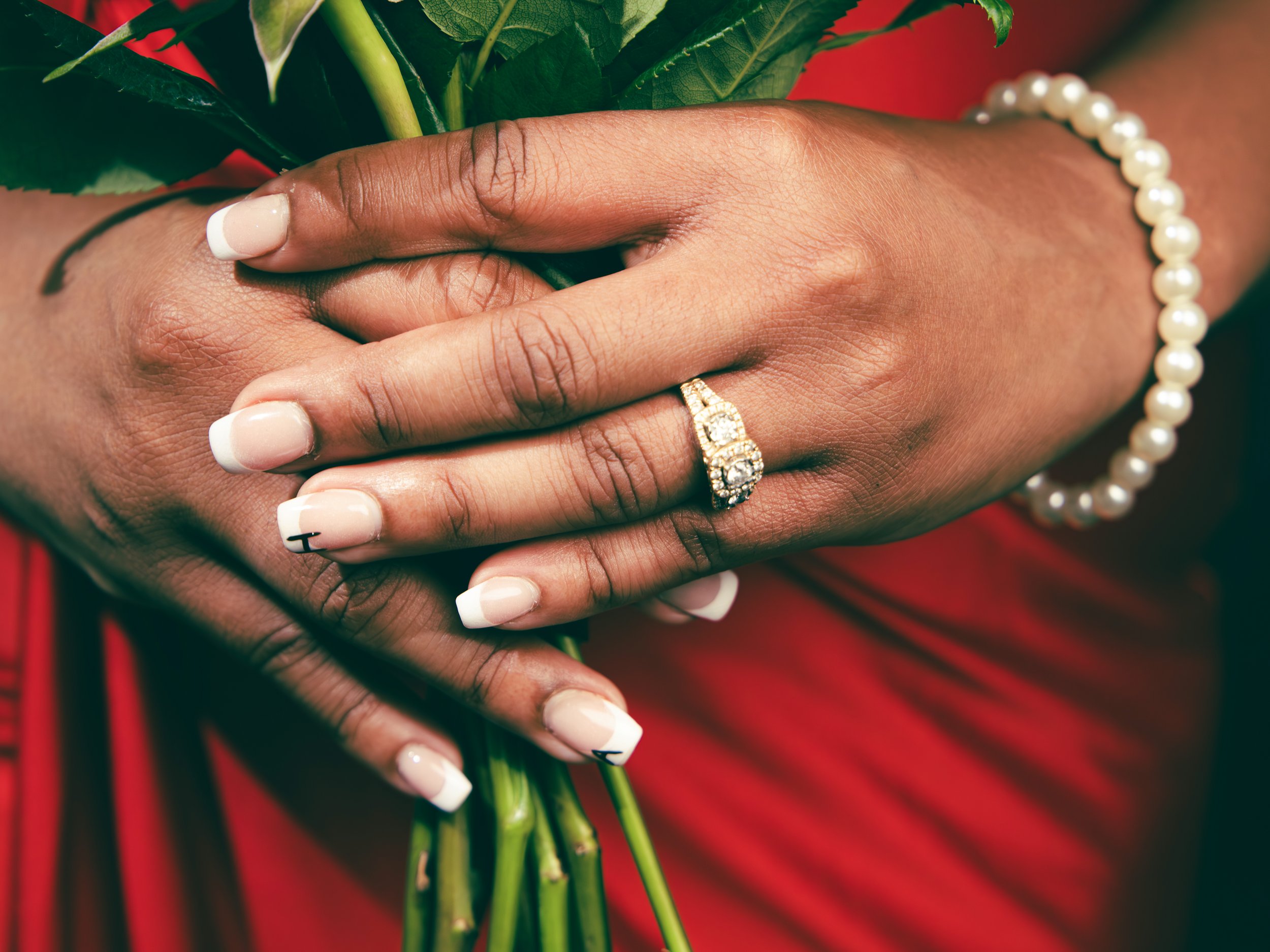 Local Dallas, Texas, DFW Non-traditional Fashion Editorial Creative Portraits Cover Art Photographer Photoshoot. Wedding Details . Close-up of hands with dark skin holding green flowers, wearing a pearl bracelet and a gold ring with diamonds, with a 