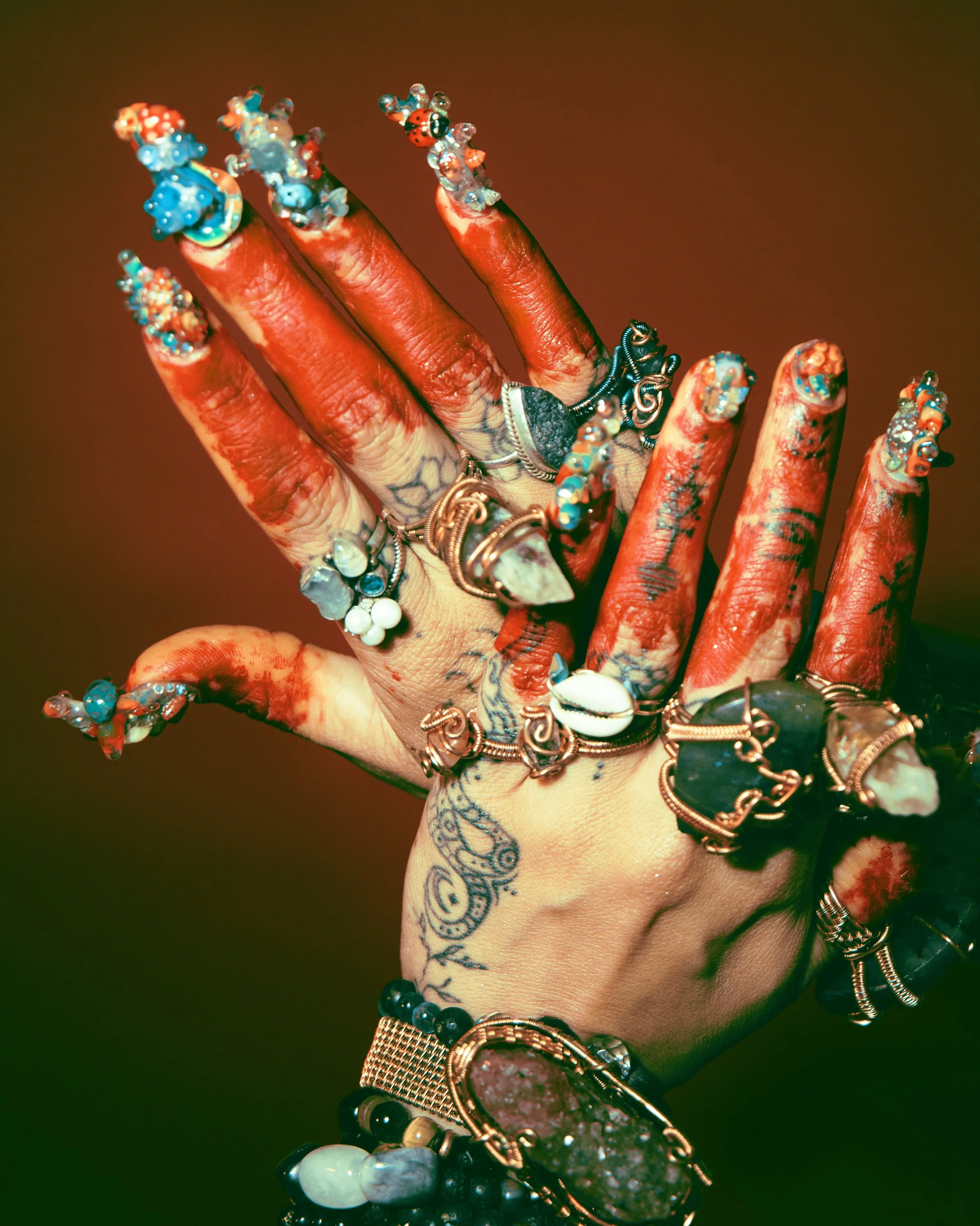 Local Dallas, Texas, DFW Non-traditional Fashion Editorial Creative Portraits Cover Art Photographer Photoshoot. A hand covered in henna tattoos, adorned with multiple rings, bracelets, and jewelry, with colorful beaded nail art on the fingers.