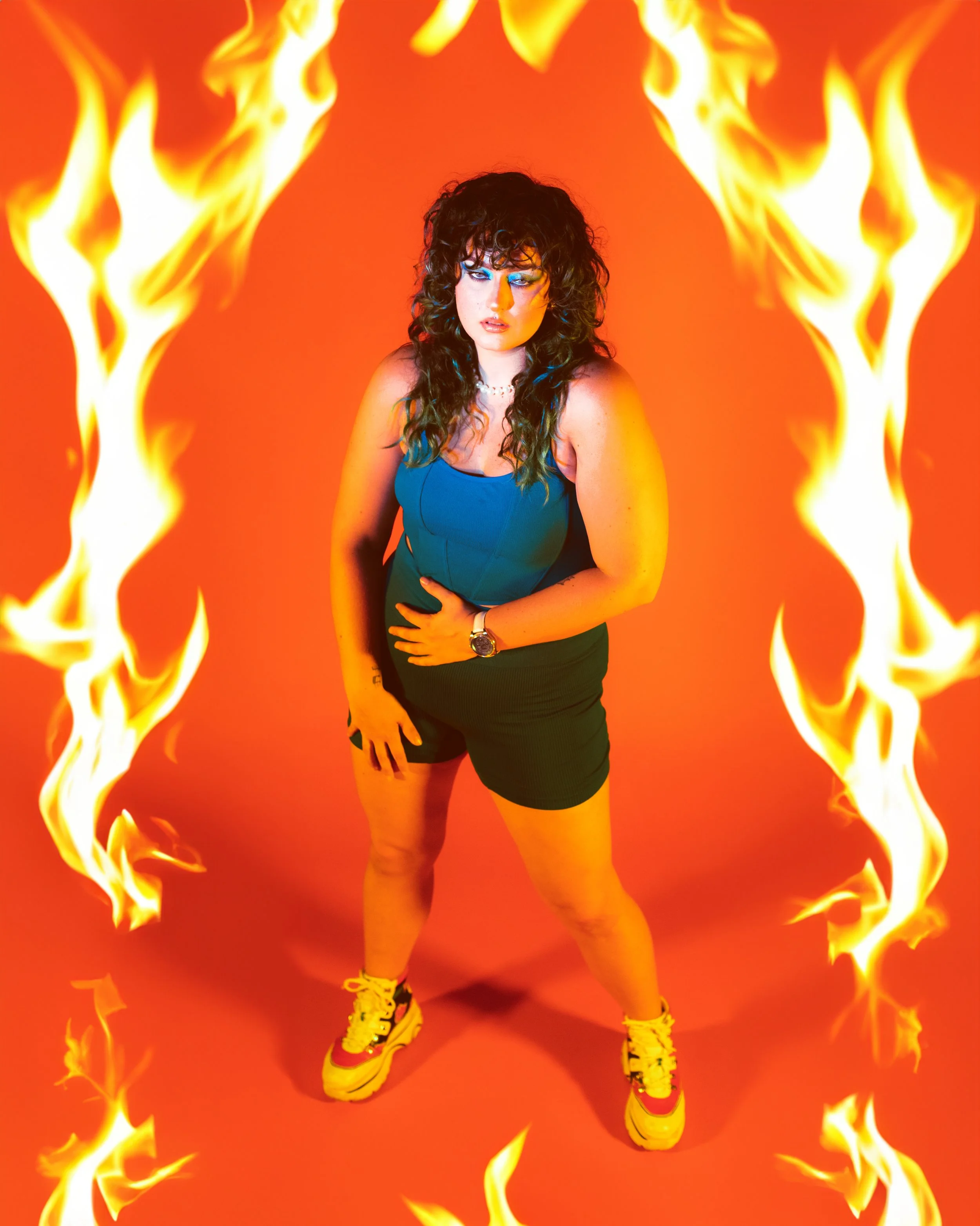 Local Dallas, Texas, DFW Non-traditional Editorial Creative Portraits Cover Art Photographer. Creative editorial portrait of local Dallas, Texas musician RAVS . A woman with curly dark hair wearing a blue top, black skirt, and bright yellow sneakers 