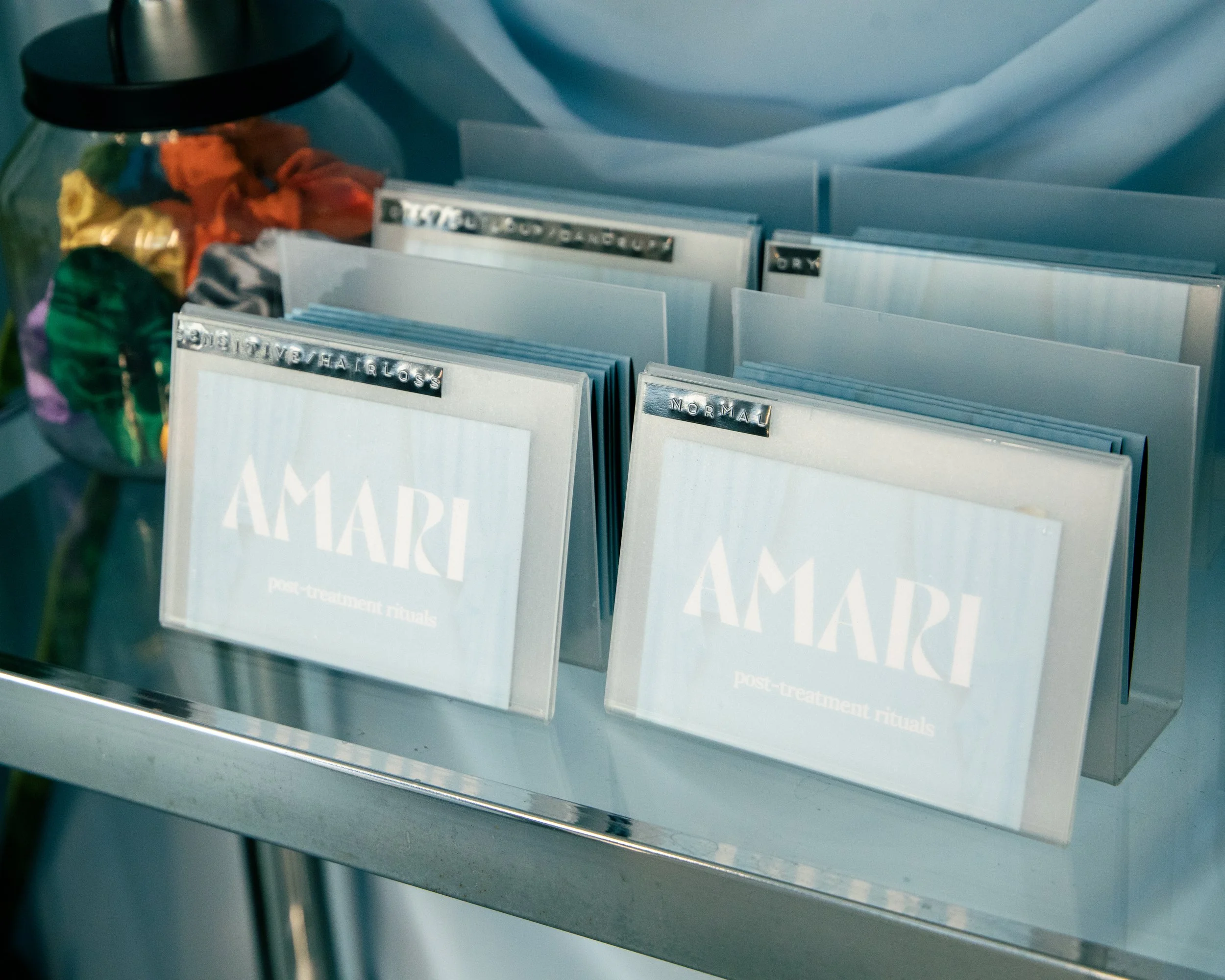 Folders with labels such as 'Normal', 'Disruptive/earlos', and others are in a display case, accompanied by a glass bowl filled with colorful wrapped candies, all placed on a metal surface.