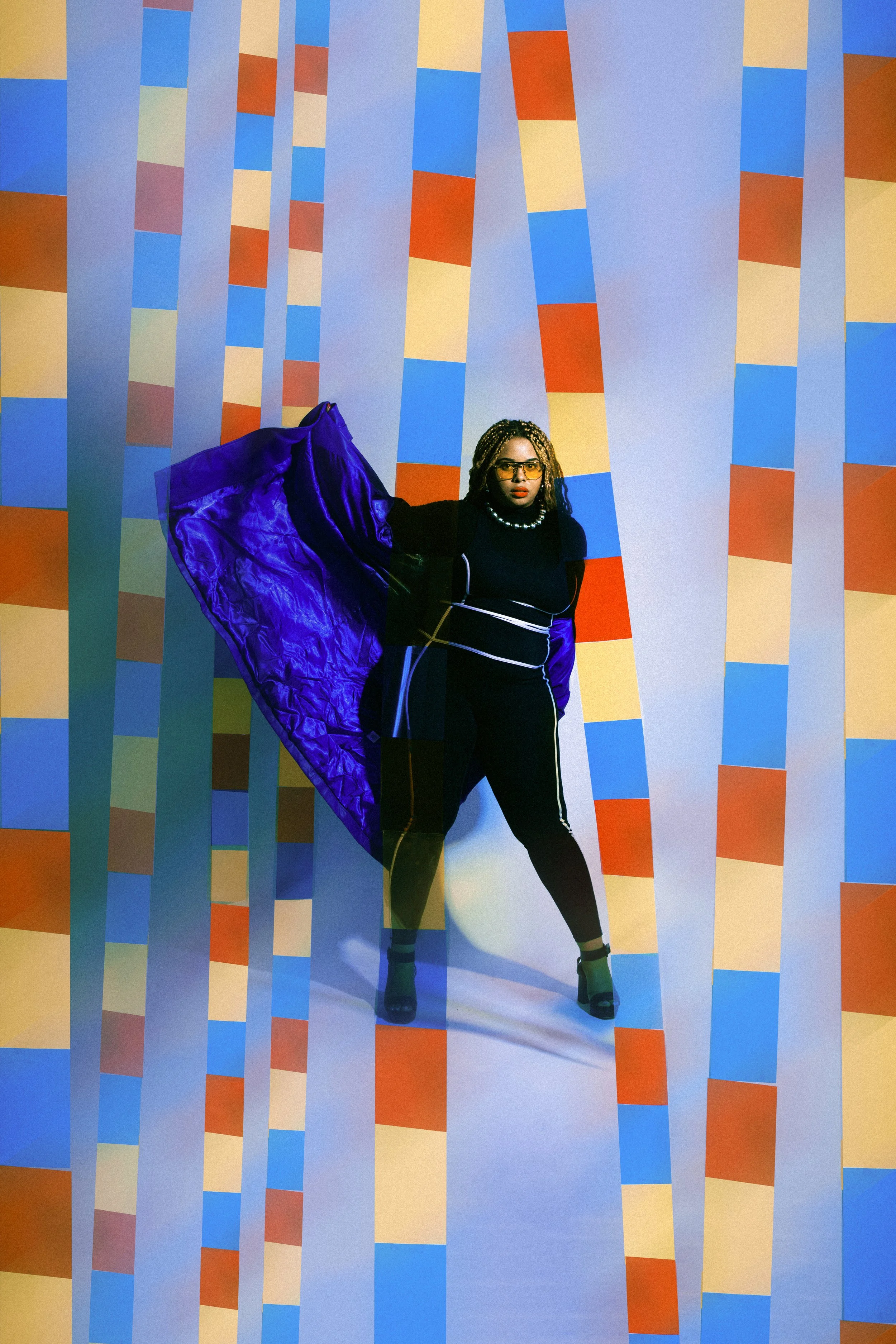 Local Dallas, Texas, DFW Non-traditional Fashion Editorial Creative Portraits Cover Art Photographer Photoshoot. A woman stands against a colorful geometric patterned background with vertical lines in various shades of blue, orange, beige, pink, and 