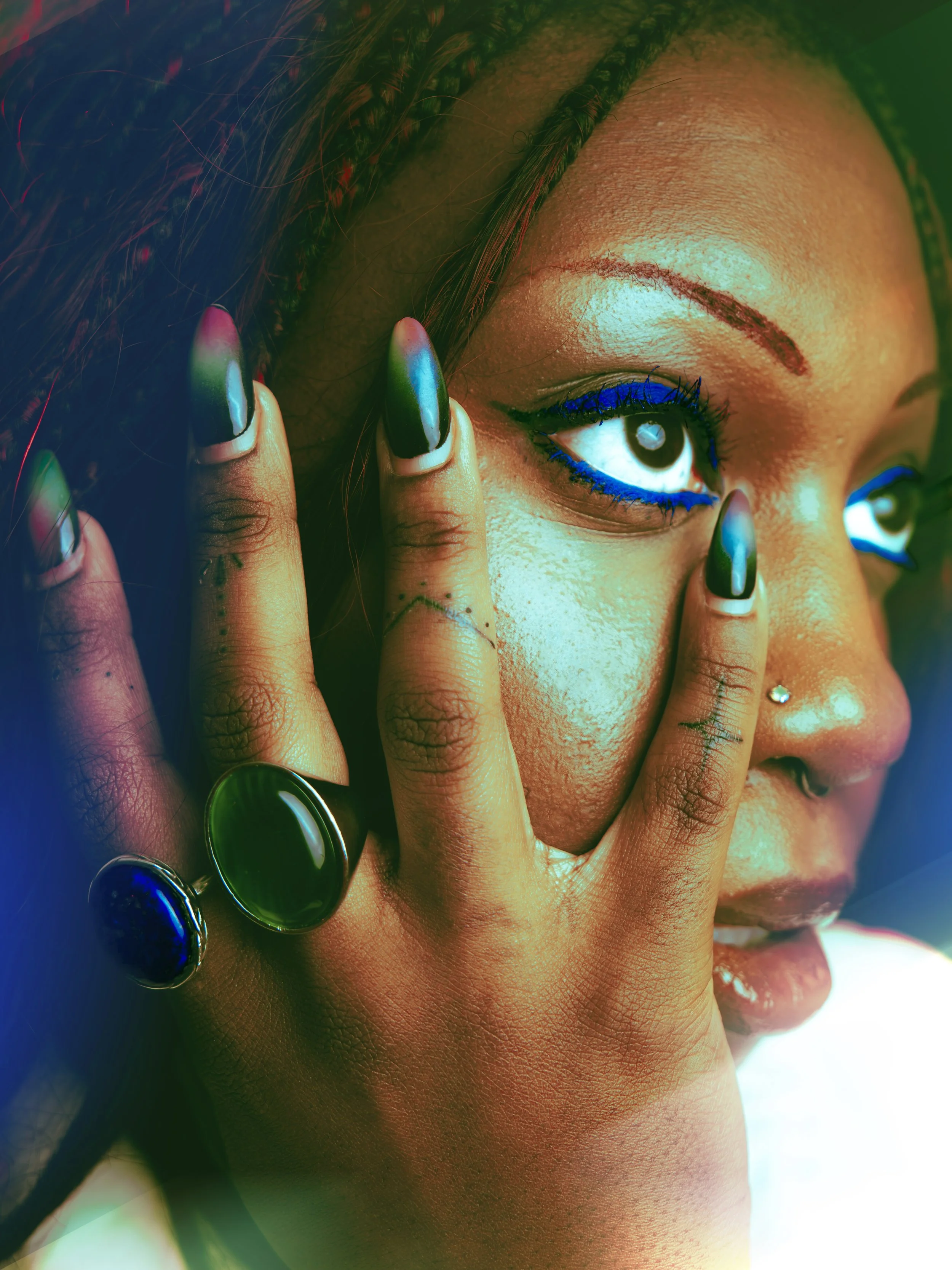 Local Dallas, Texas, DFW Non-traditional Editorial Creative Portraits Cover Art Photographer. Musician Courtney Noir of group Loading... A close-up of a woman with colorful makeup and jewelry, touching her face with her fingers.