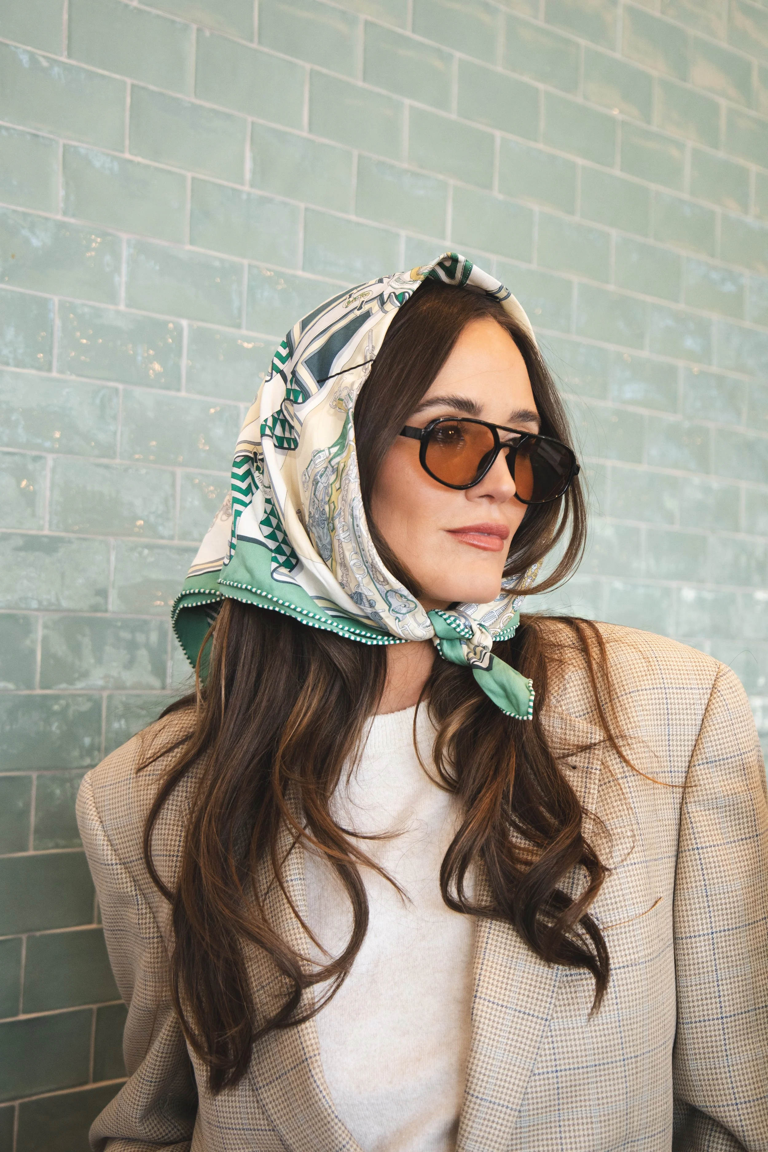 Local Dallas, Texas, DFW Non-traditional Fashion Editorial Creative Portraits Cover Art Photographer Photoshoot. Revel Workshop . A woman with long dark hair wearing sunglasses, a patterned scarf, a white top, and a beige checkered blazer, standing a