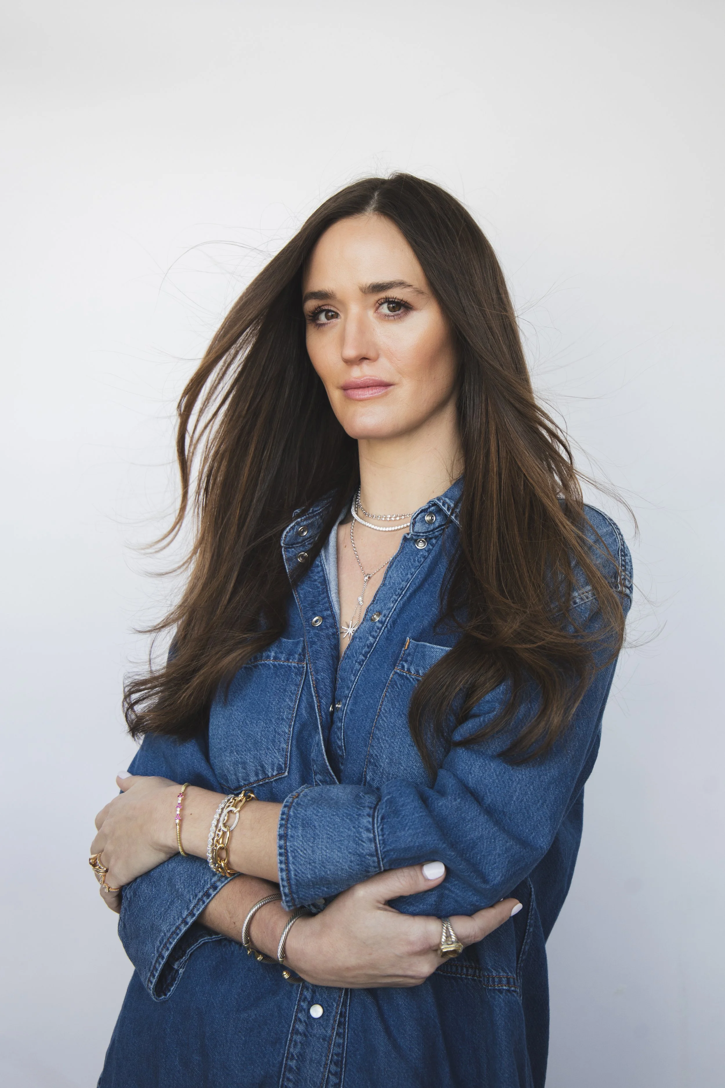 Local Dallas, Texas, DFW Non-traditional Fashion Editorial Creative Portraits Cover Art Photographer Photoshoot. Revel Workshop. A woman with long dark hair wearing a denim jacket and multiple jewelry pieces, including necklaces and bracelets, stands