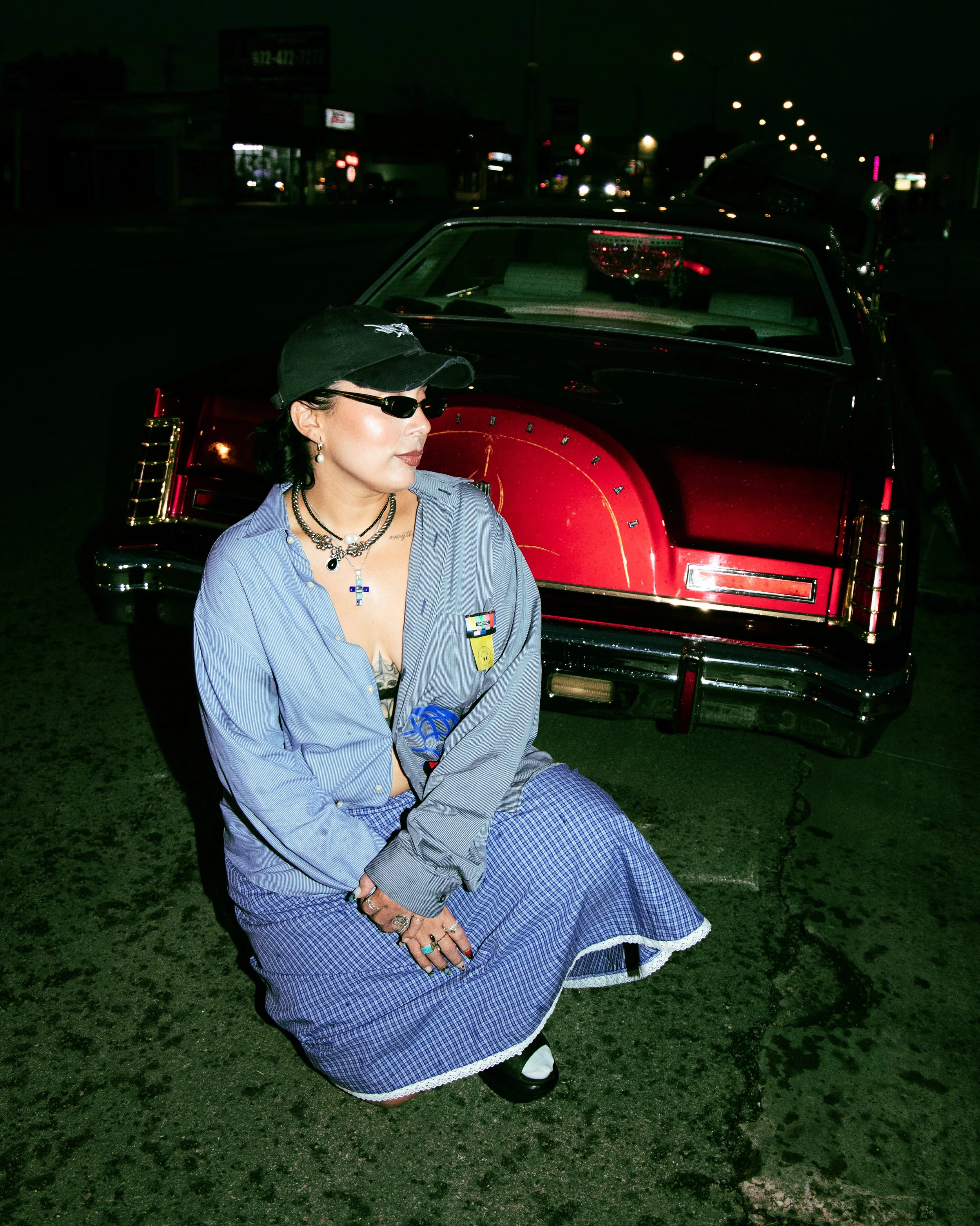 Local Dallas, Texas, DFW Non-traditional Fashion Editorial Creative Portraits Cover Art Photographer Photoshoot. Nataly Medina Crecer Dallas . A woman with dark hair, wearing sunglasses, a black cap, blue striped shirt, and a blue skirt with a white 