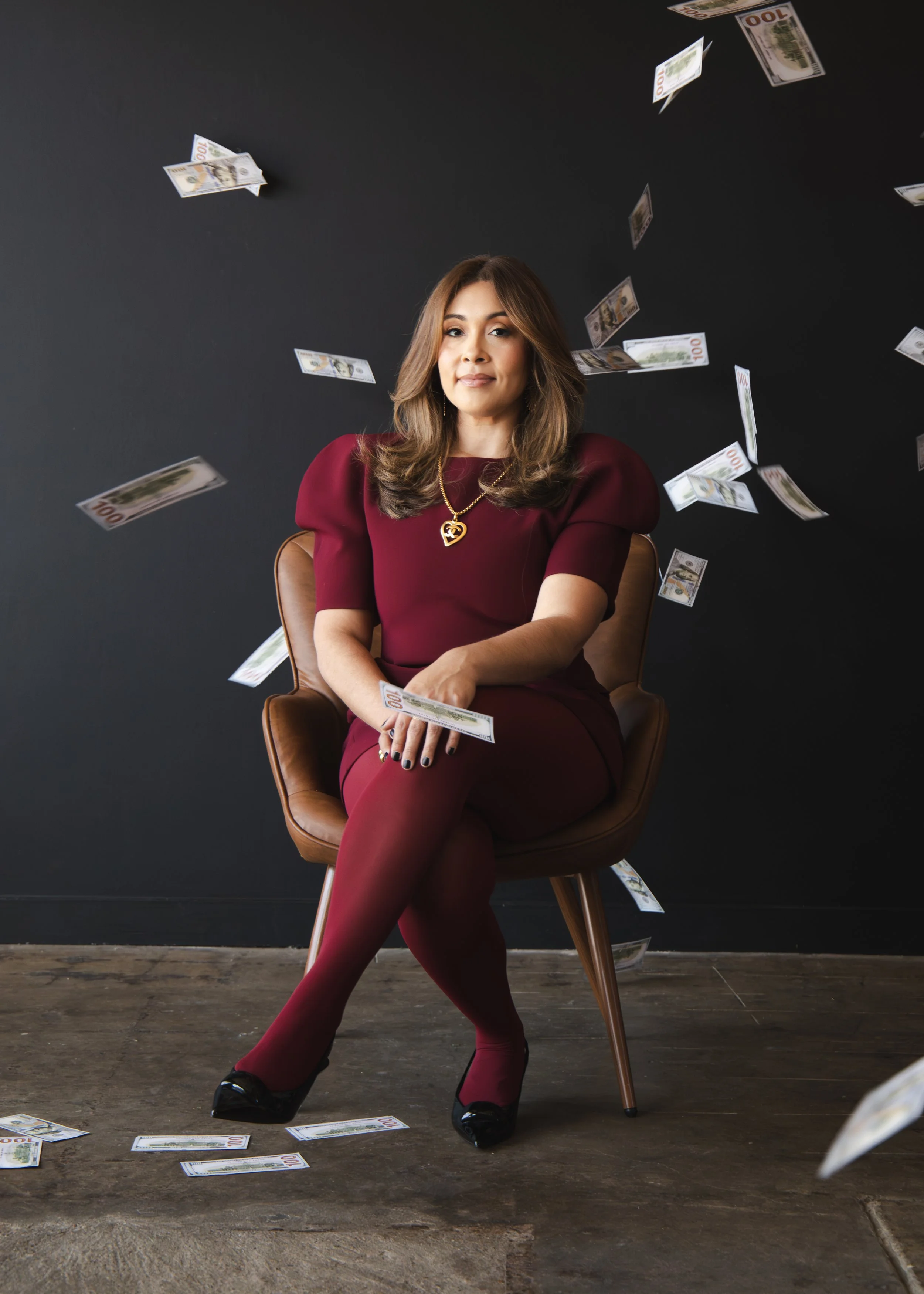 Local Dallas, Texas, DFW Non-traditional Fashion Editorial Creative Portraits Cover Art Photographer Photoshoot. Adriana Martinez, Revel Workshop. Vida Wealth Club . A woman in a red dress sitting on a chair with floating and scattered 100 dollar bil