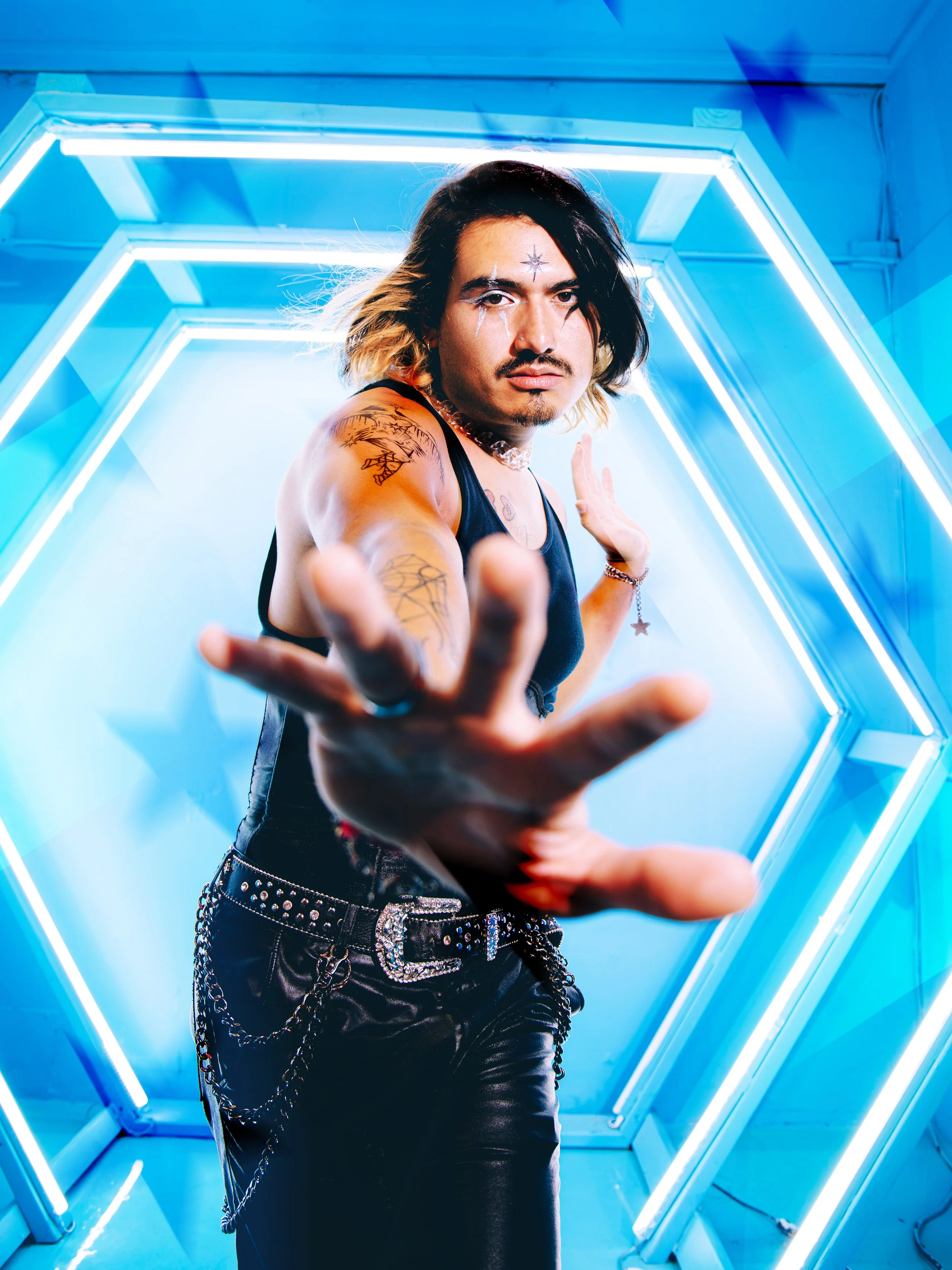 Local Dallas, Texas, DFW Non-traditional Fashion Editorial Creative Portraits Cover Art Photographer Photoshoot. Musician Yonose . Person with tattooed arm and black and blonde hair in a black tank top, reaching toward the camera, inside a glowing bl