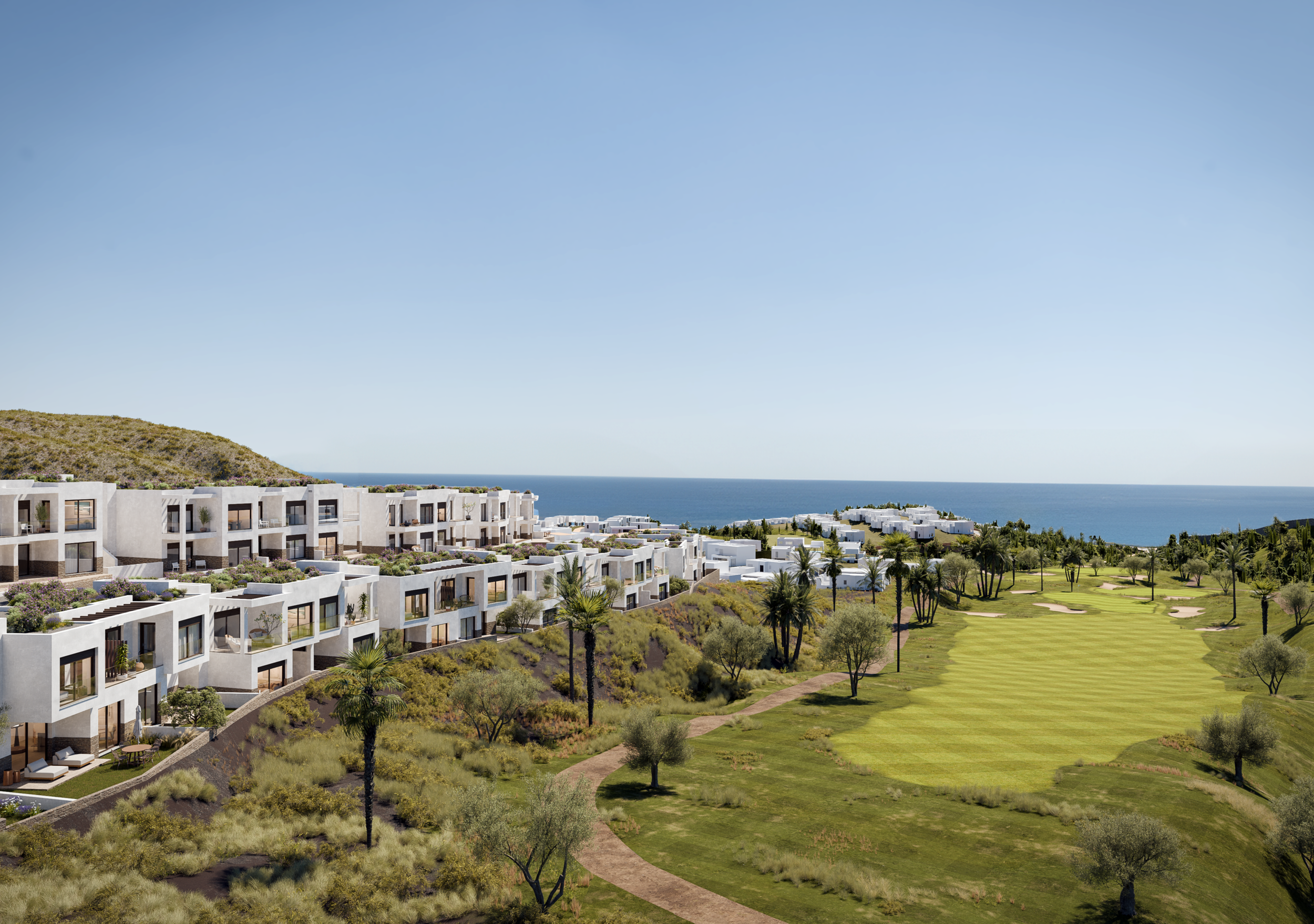 High-rise white apartment buildings with balconies facing a green golf course, overlooking the ocean and a mountain.