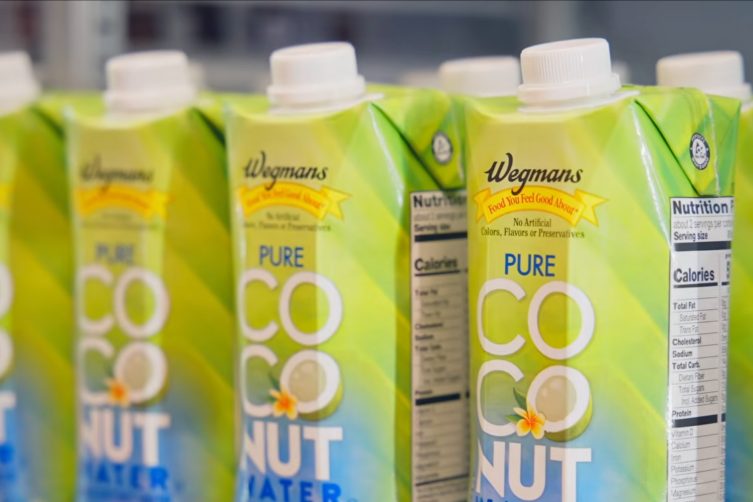 Cartons of Wegmans Pure Coconut Water with green packaging and white caps on a store shelf.