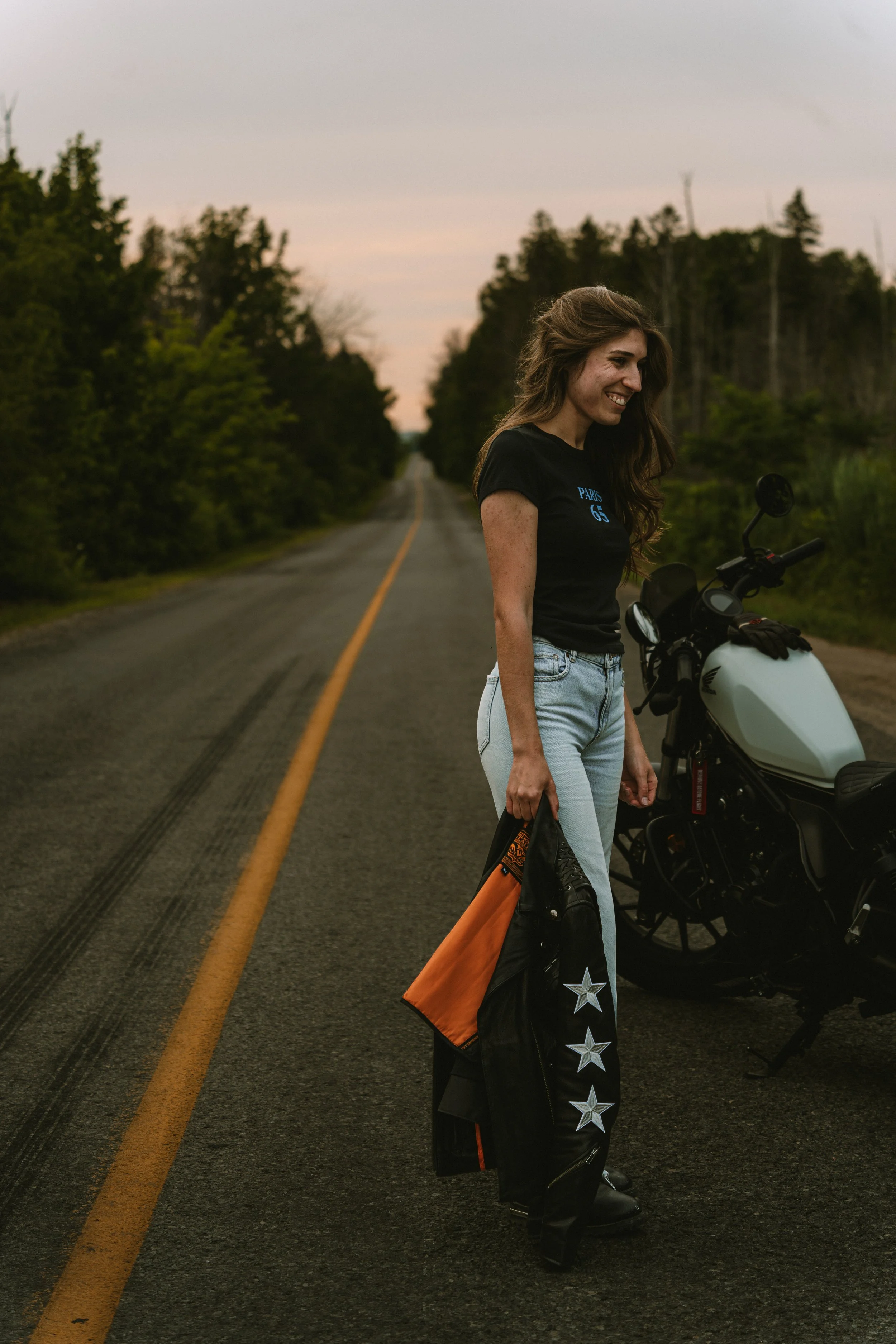 Portrait lifestyle d’une femme avec sa moto, capturé dans un moment naturel et spontané en extérieur.