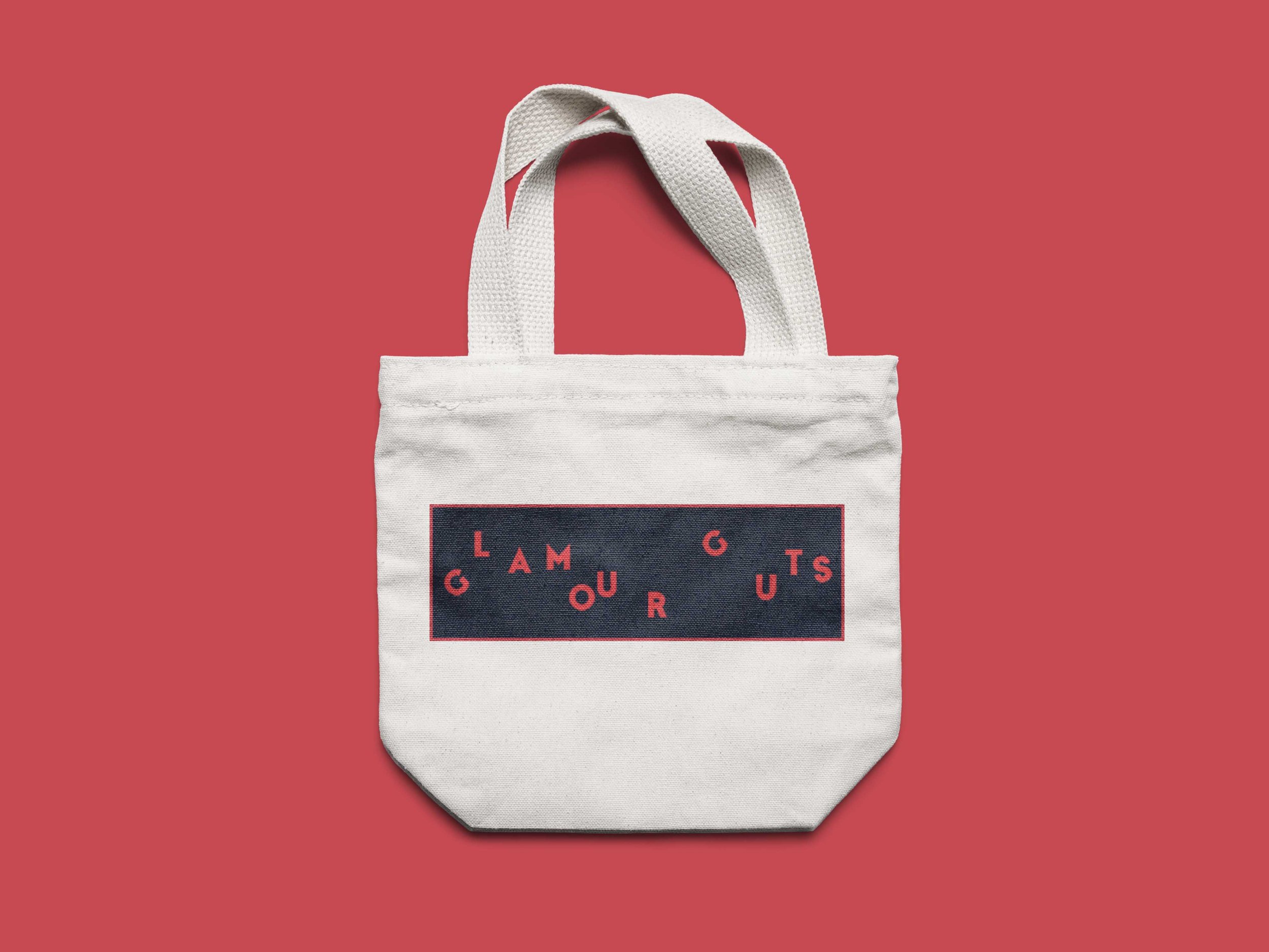 A white tote bag with a dark rectangular logo and red lettering on a red background.