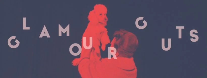 A woman holding a small dog with letters spelling 'Glamour Guts' surrounding them.