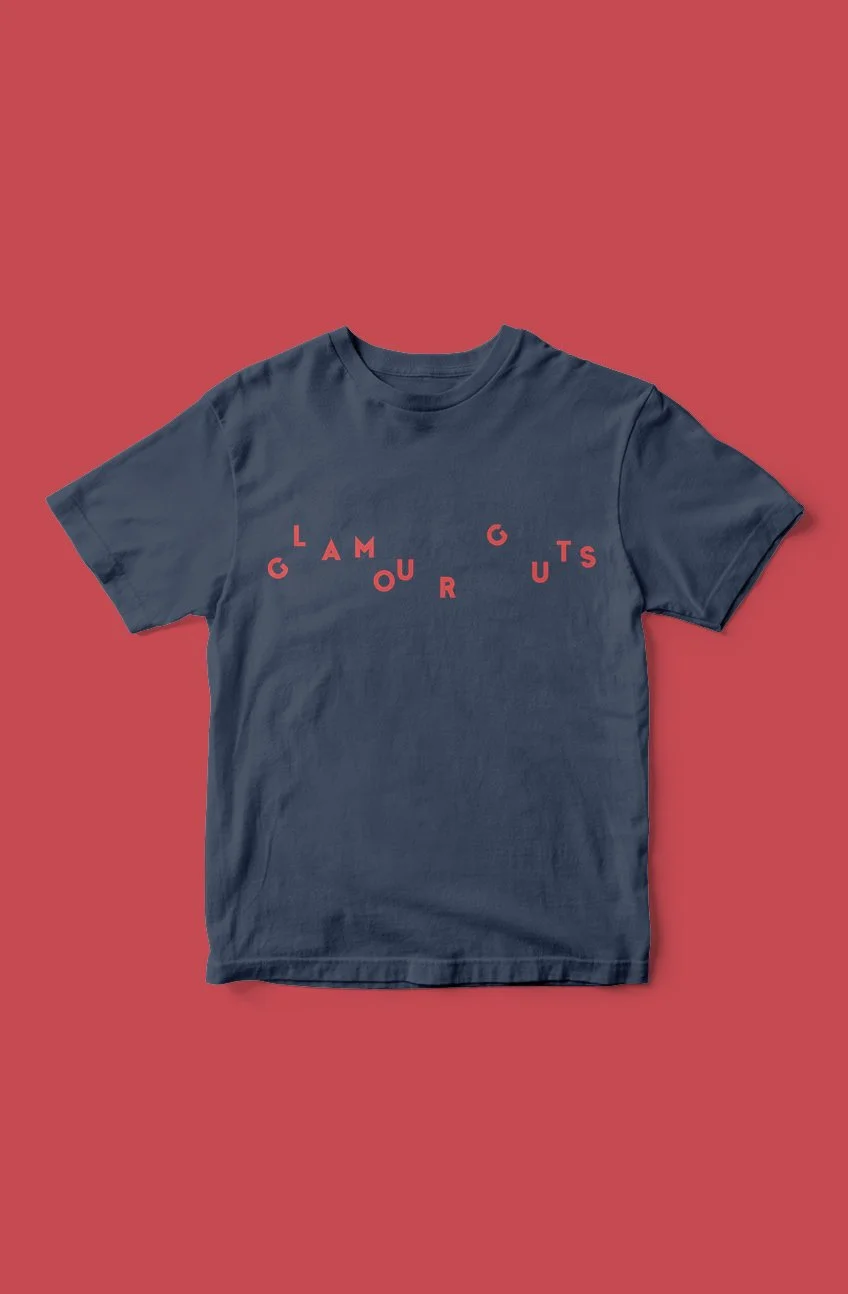 A navy blue T-shirt with red letters spelling out "GAMOUR" arranged in a curved pattern on a red background.