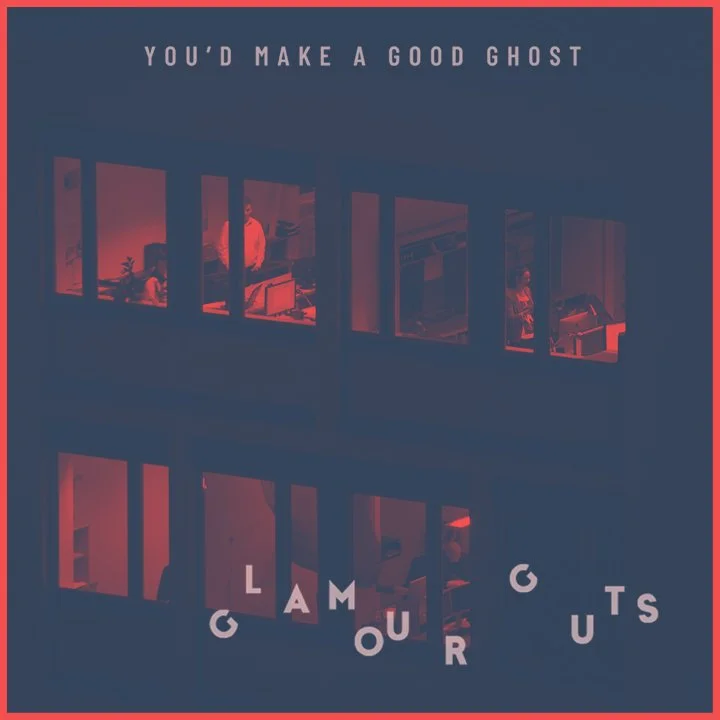 Photo of a building at night with illuminated office rooms, some with people working at desks. Text at the top reads 'You'd make a good ghost' and at the bottom 'Glamour Guts'.