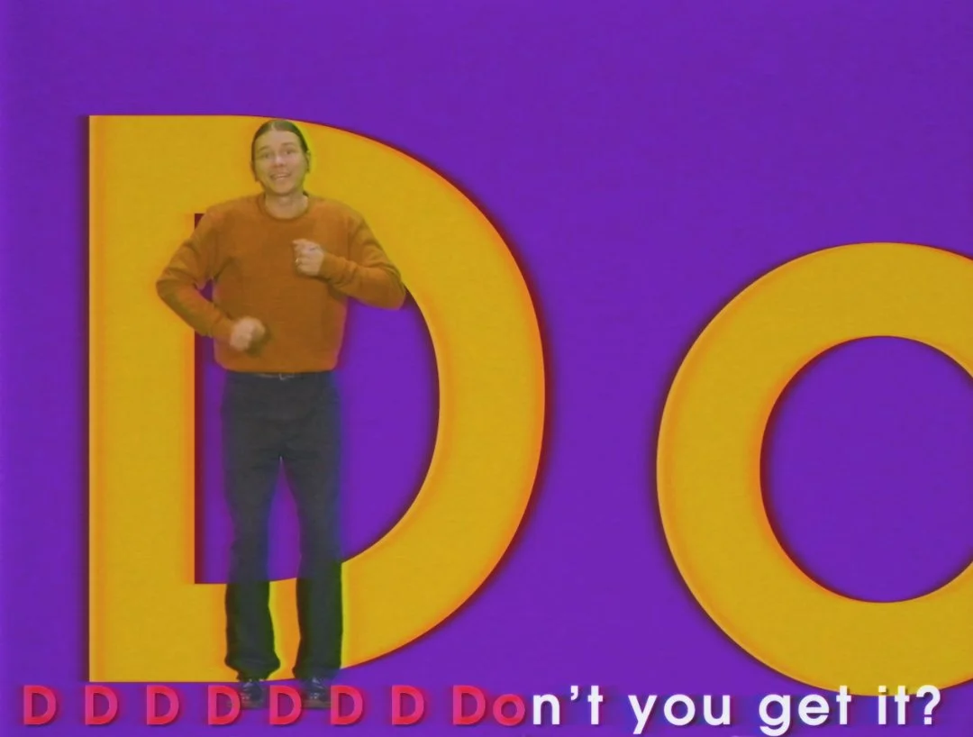 A woman in a brown sweater standing in front of a colorful purple and yellow background with large yellow letters 'D' and 'O'. There are red letter 'D's' and the text 'Don't you get it?' at the bottom.