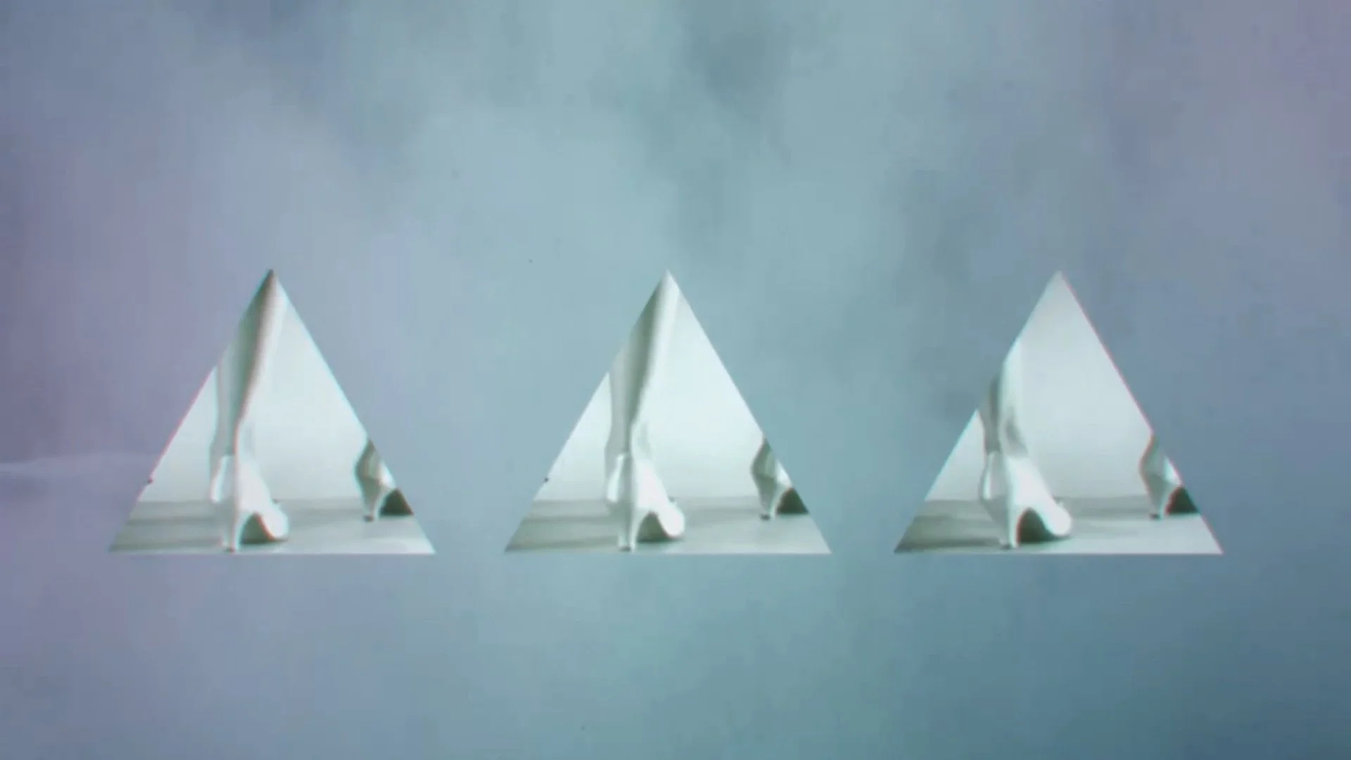 Three white paper art sculptures of mountains with snowy peaks on a white surface against a light blue background.