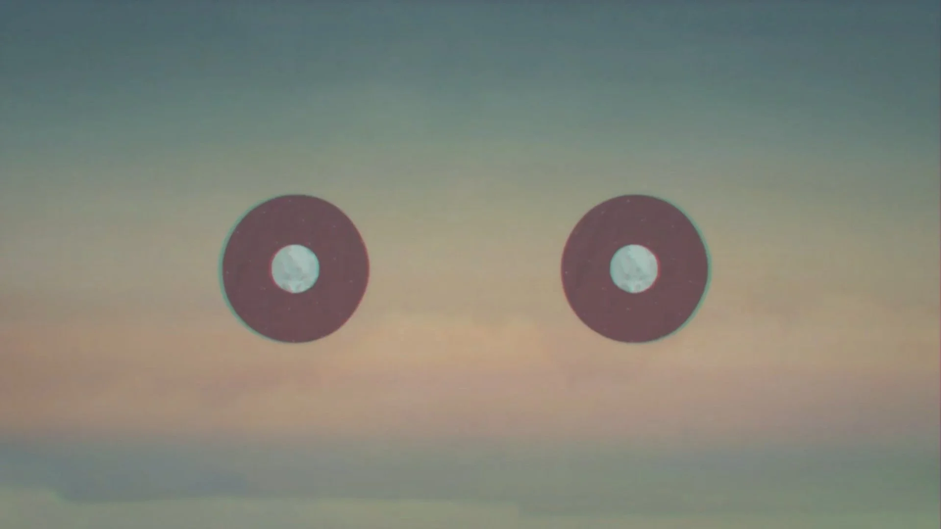 Two circular objects with black outer ring and white center on a gradient background.