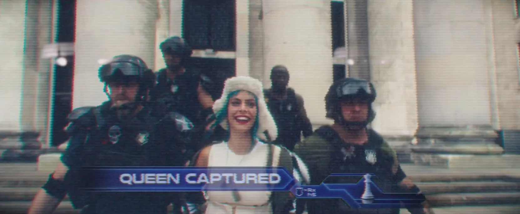 A woman with white hair smiling in front of police officers wearing helmets and tactical gear, standing on steps in front of a building, with the caption "Queen Captured" at the bottom.