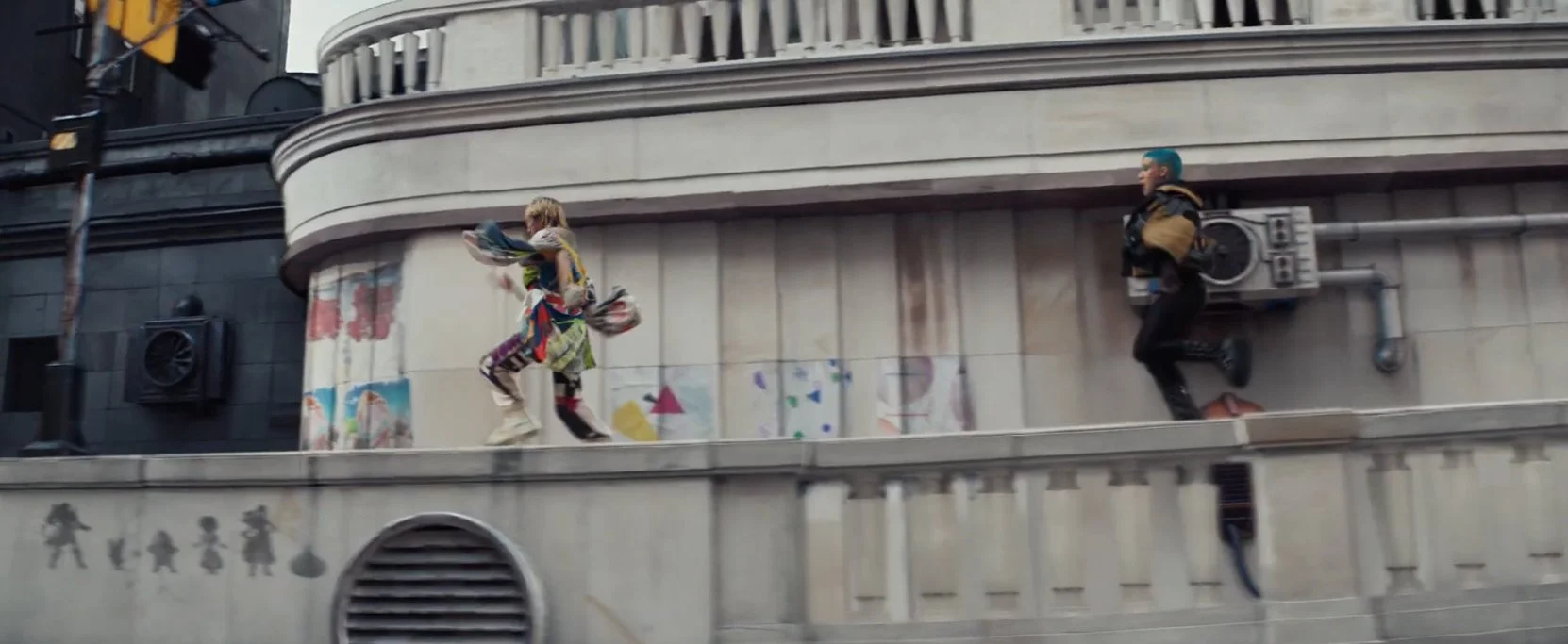 Two individuals running along a city building ledge, one with blue hair and the other with blonde hair, wearing colorful outfits.