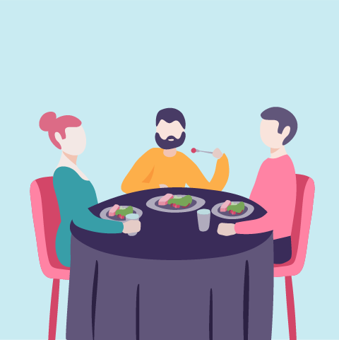 Three people sitting at a round table enjoying a meal together, with plates of food and drinks.