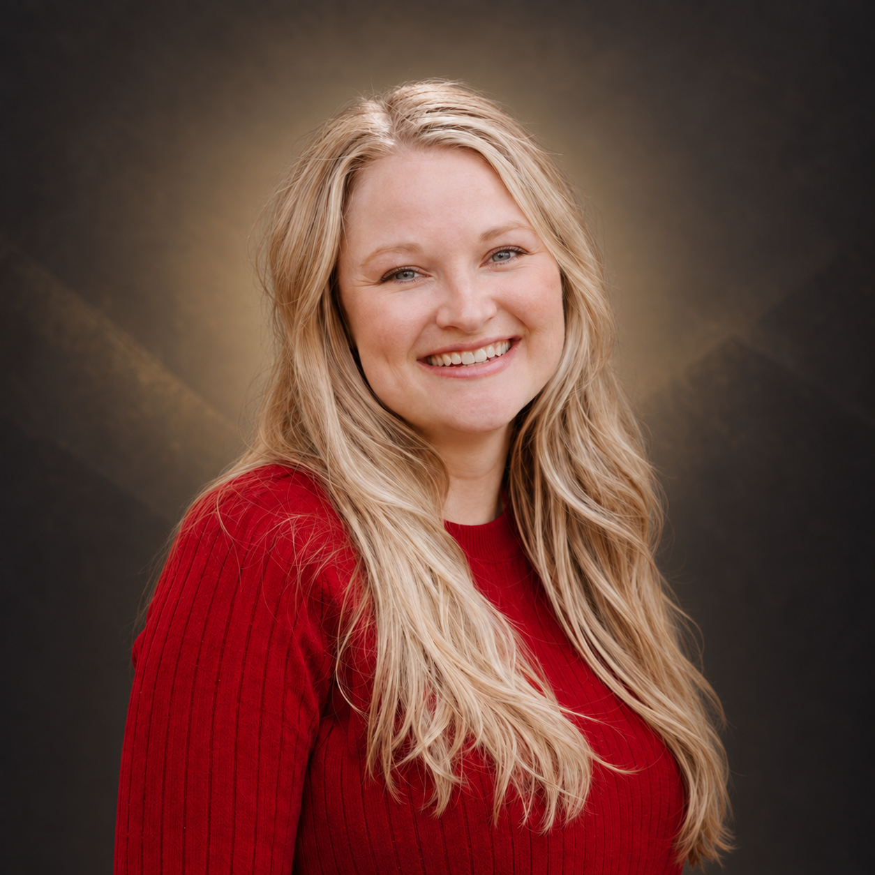 Portrait of a smiling woman with long blonde hair, wearing a red sweater, against a dark brown and gold gradient background.