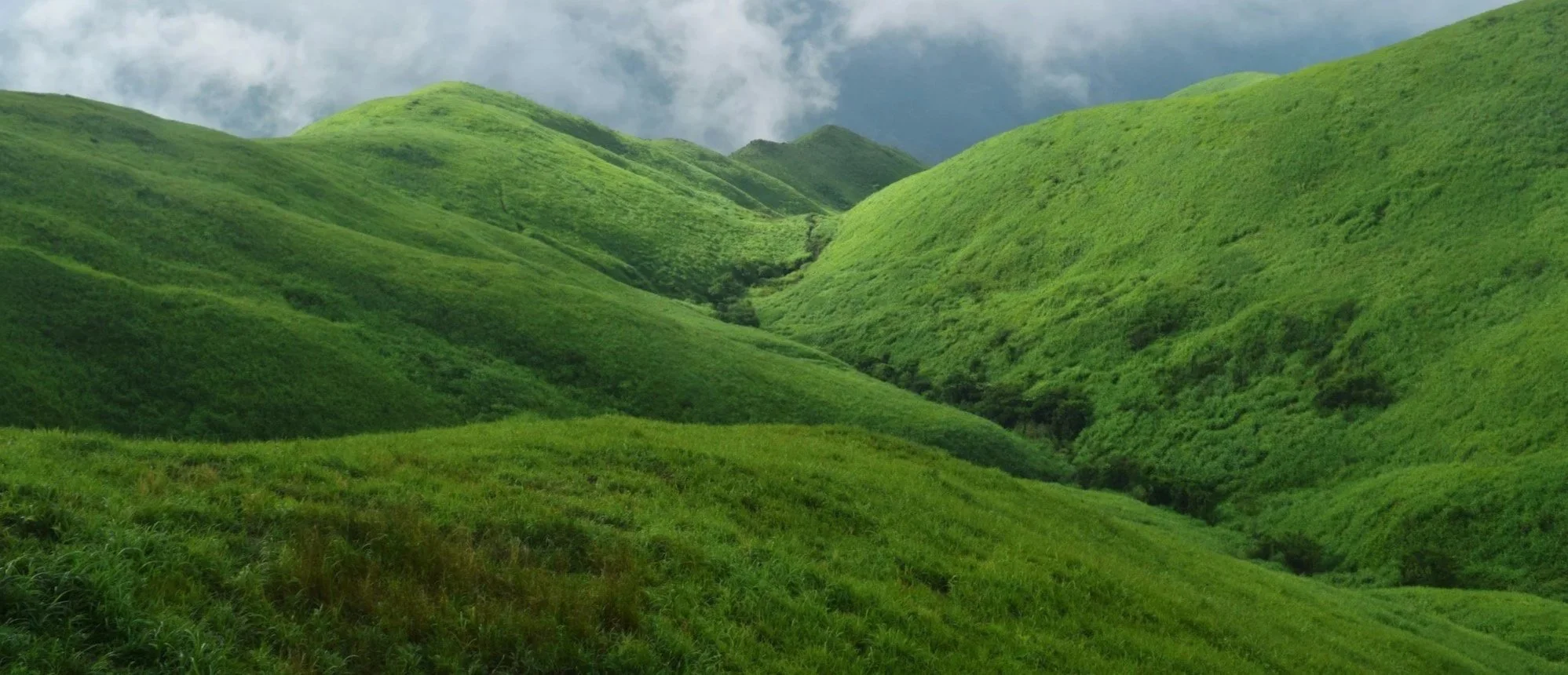 Green rolling hills under a cloudy sky.