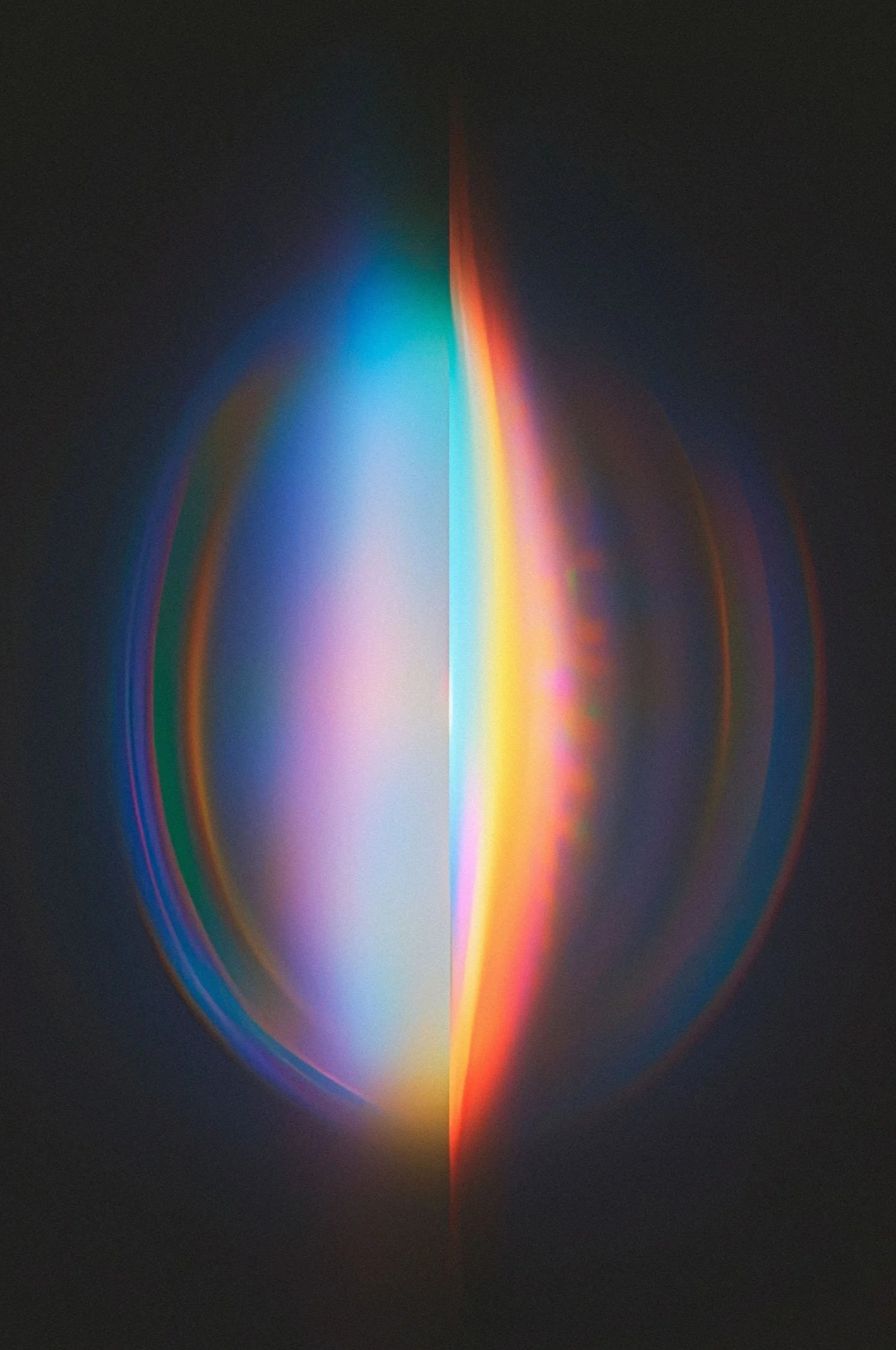 A dark background with a glowing, multicolored vertical light beam showing shades of blue, green, yellow, orange, red, and pink.