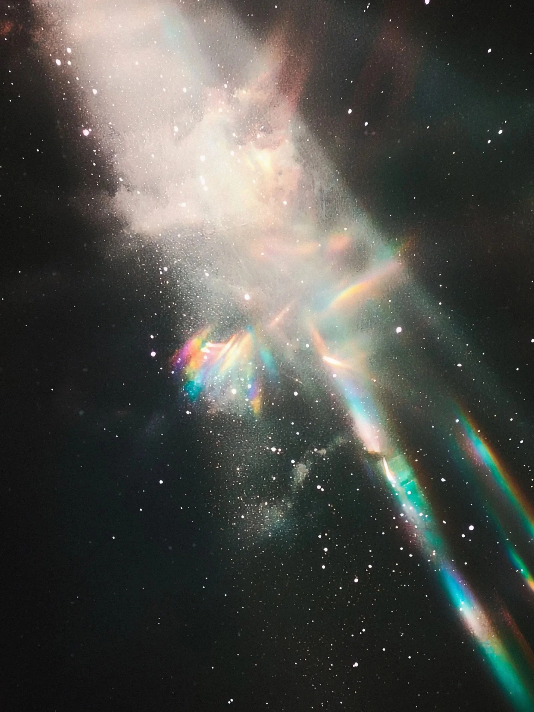 A photo of space with stars, gases, and colorful light reflections.