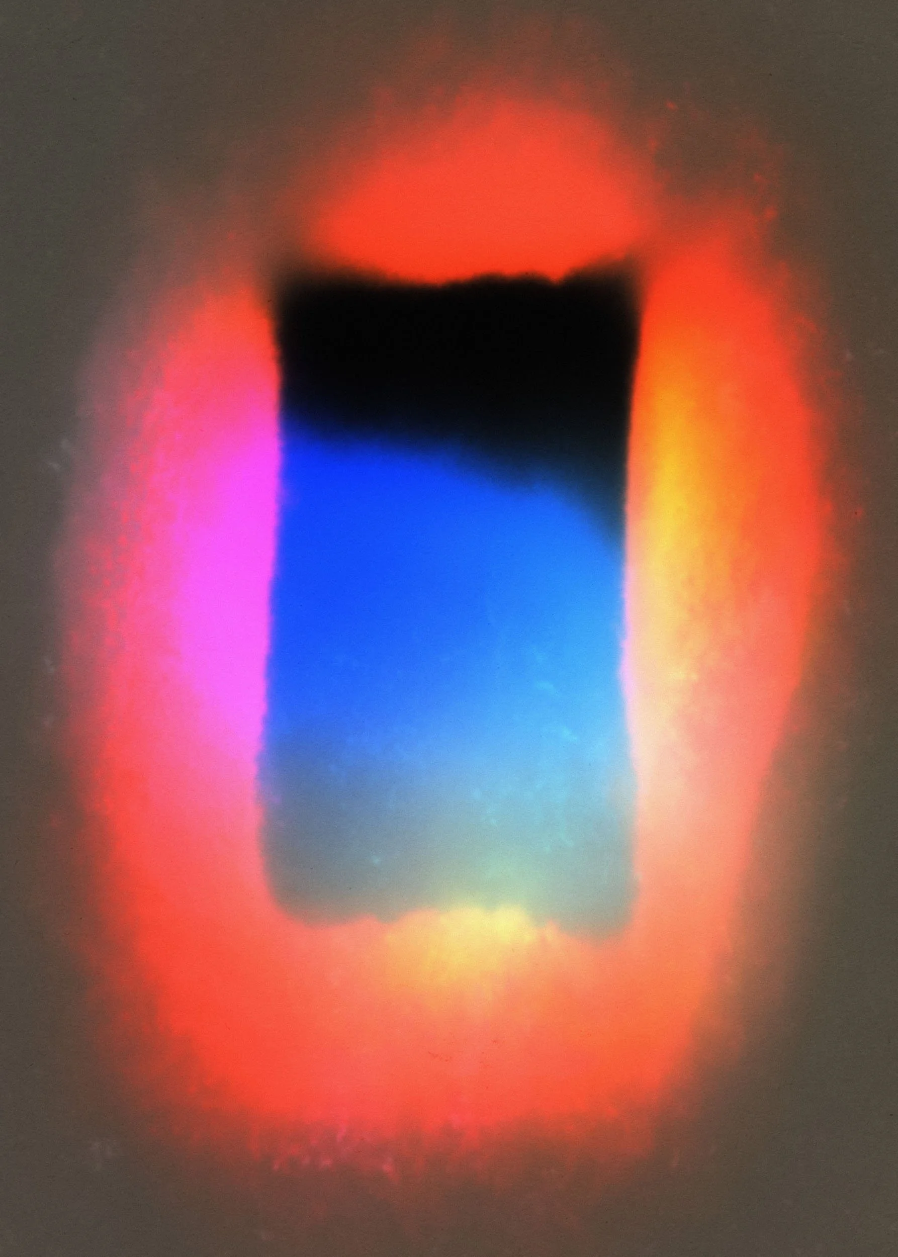Close-up of a dark object with a colorful rainbow aura around it, featuring shades of blue, pink, yellow, and red.