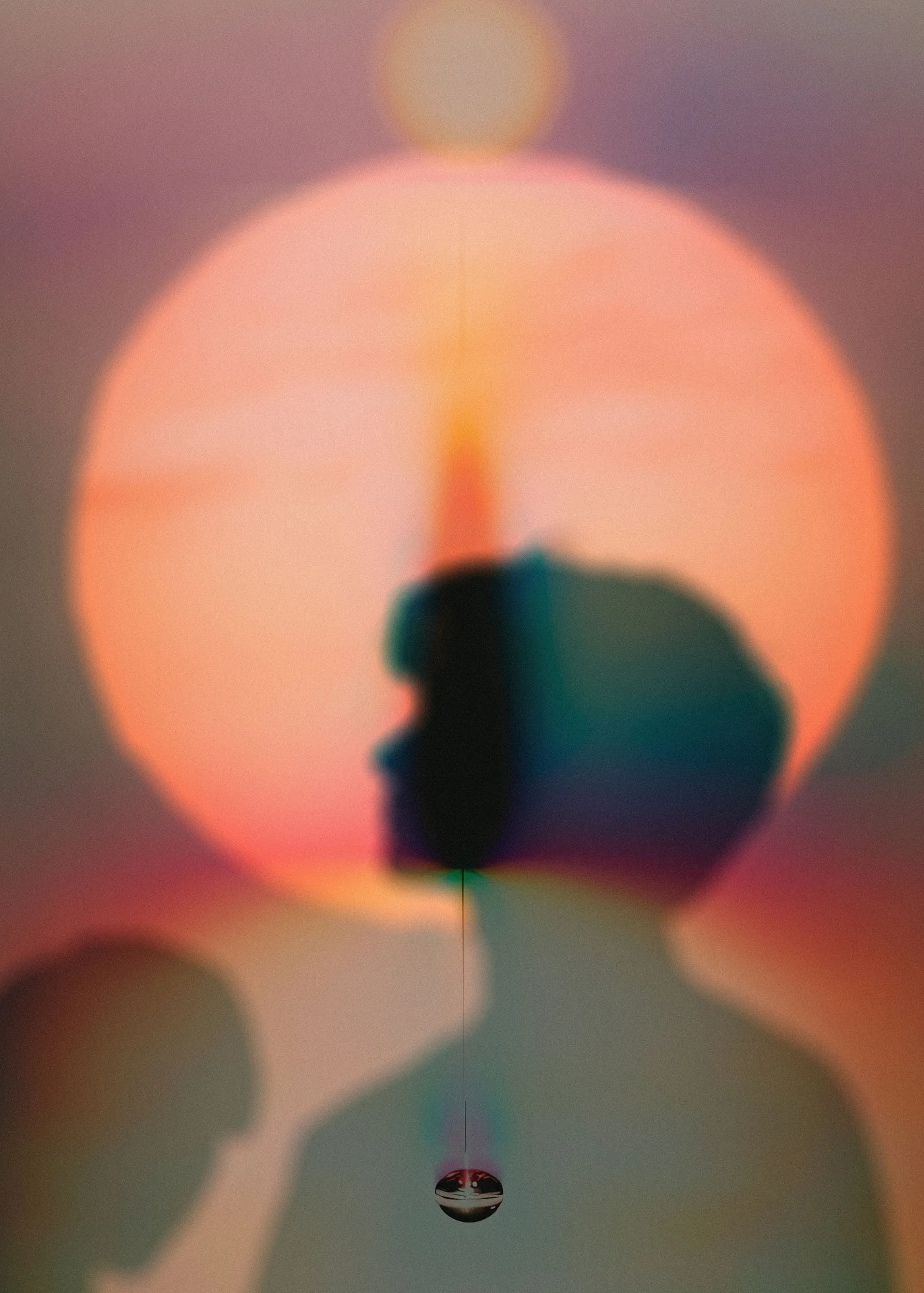 Close-up of a drop of water hanging from a surface, with a reflected image at the bottom and a blurry background with colorful bokeh lights.